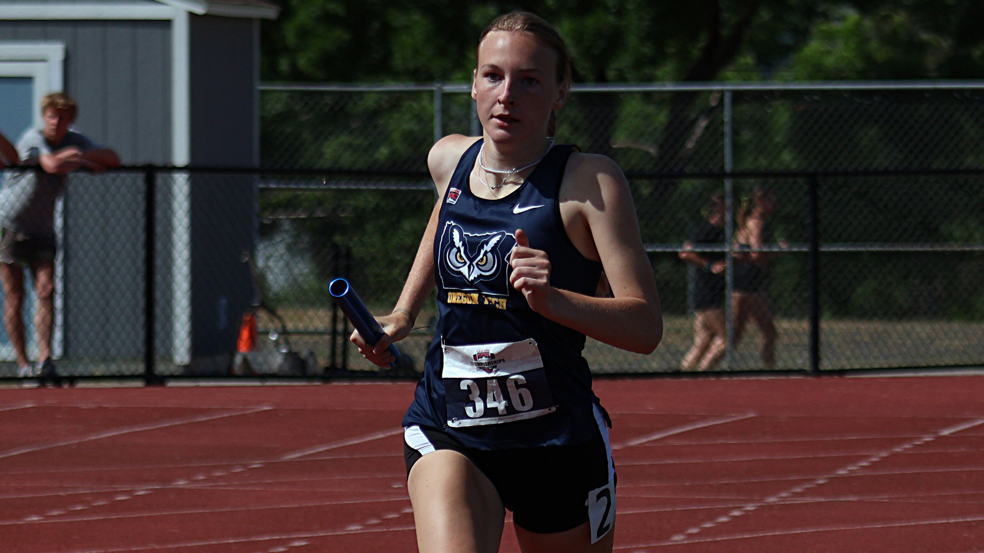 Lily Everson running with a baton on straightaway of track