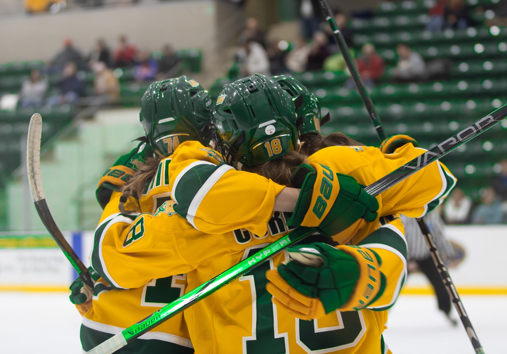 Three Lakers hugging to celebrate a goal being scored