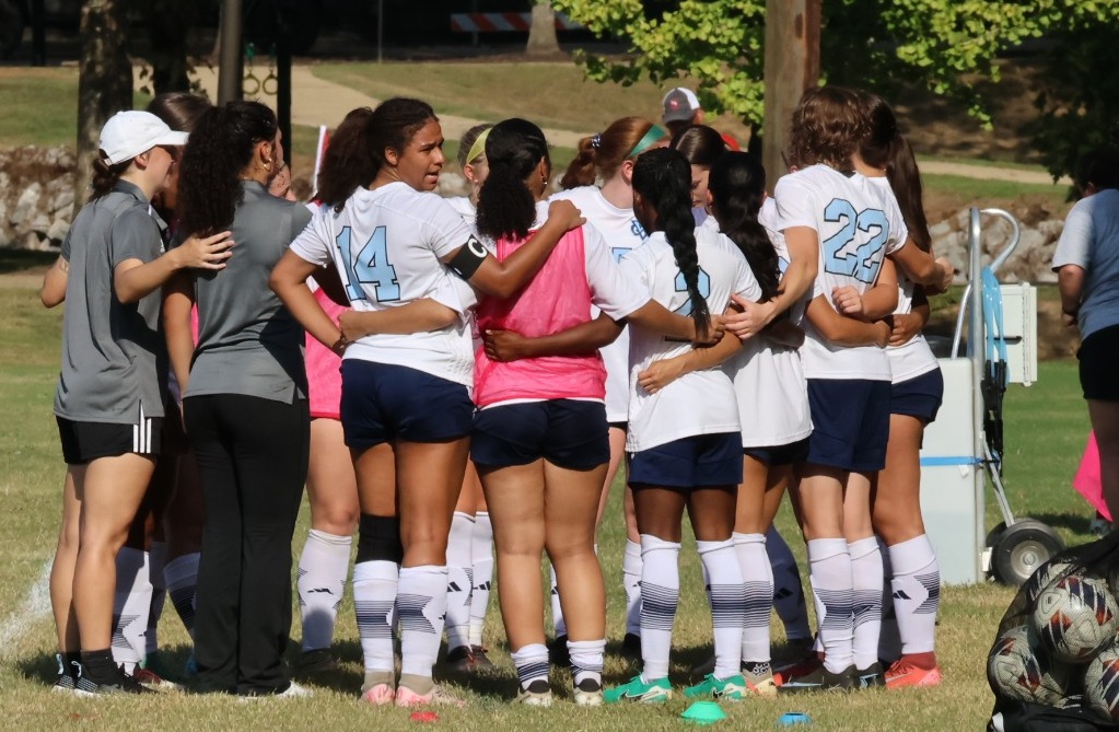 The W women's soccer team in a pre-game huddle