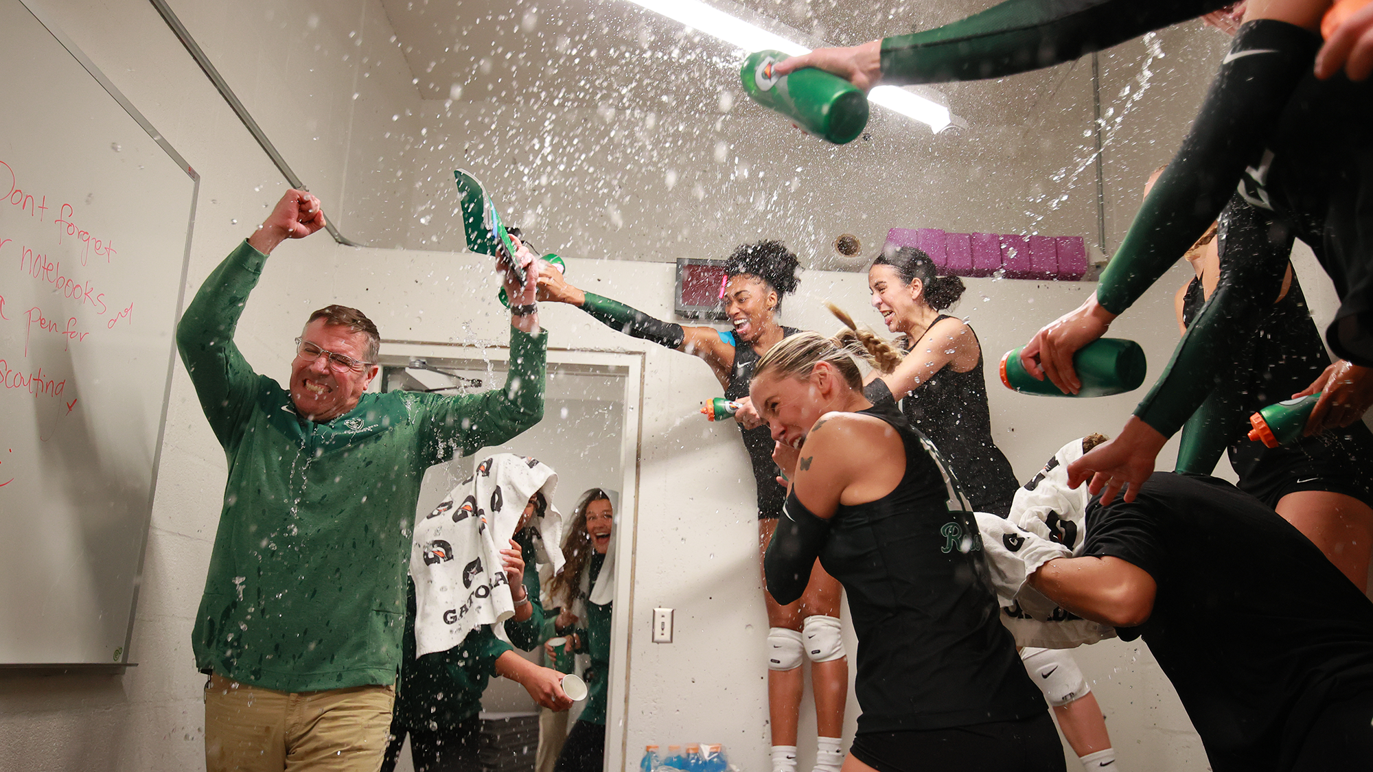 The Portland State volleyball team sprays water on head coach Michael Seemann after its win over Utah.