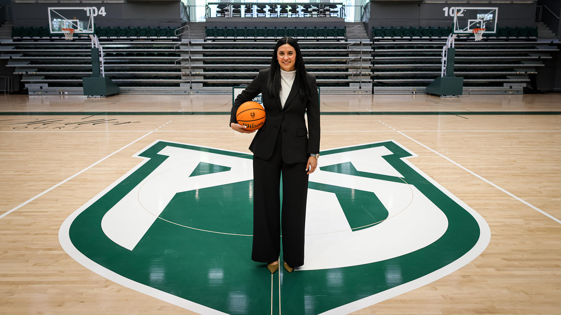 New Portland State women's basketball coach Karlie Burris poses for a photo at mid-court in Viking Pavilion