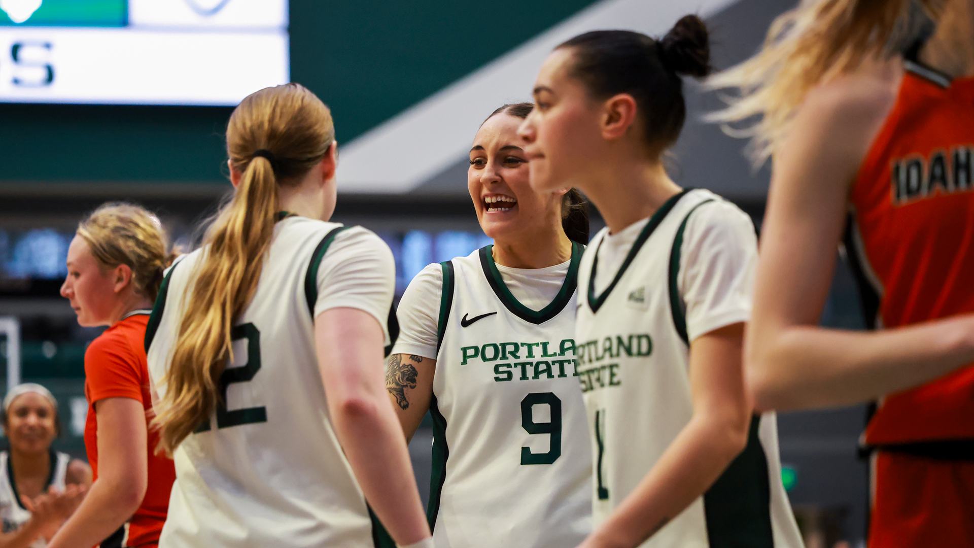 Portland State women's basketball players huddle together after teammate Kyleigh Brown scores while being fouled.