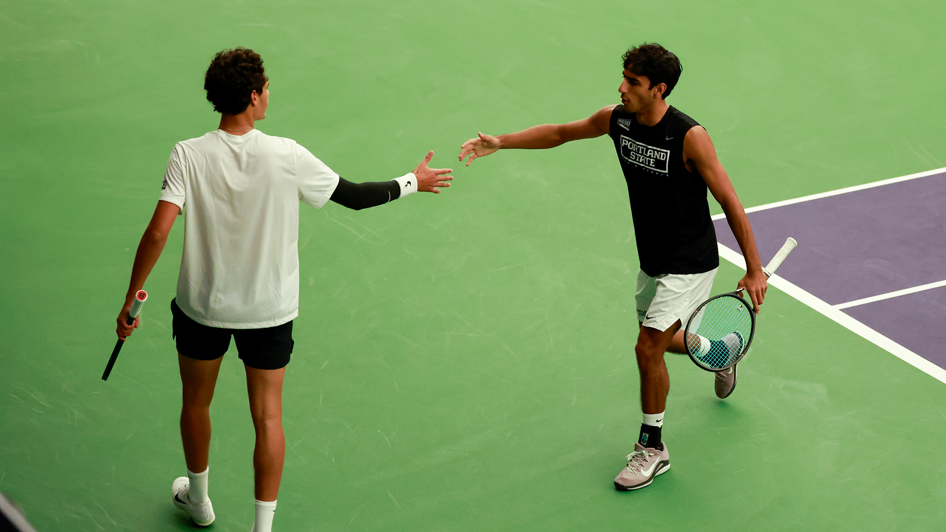 Portland State men's tennis players Maas Schotanus and Aarjun Pandit high five each other during their championship match at the ITA Northwest Regional.