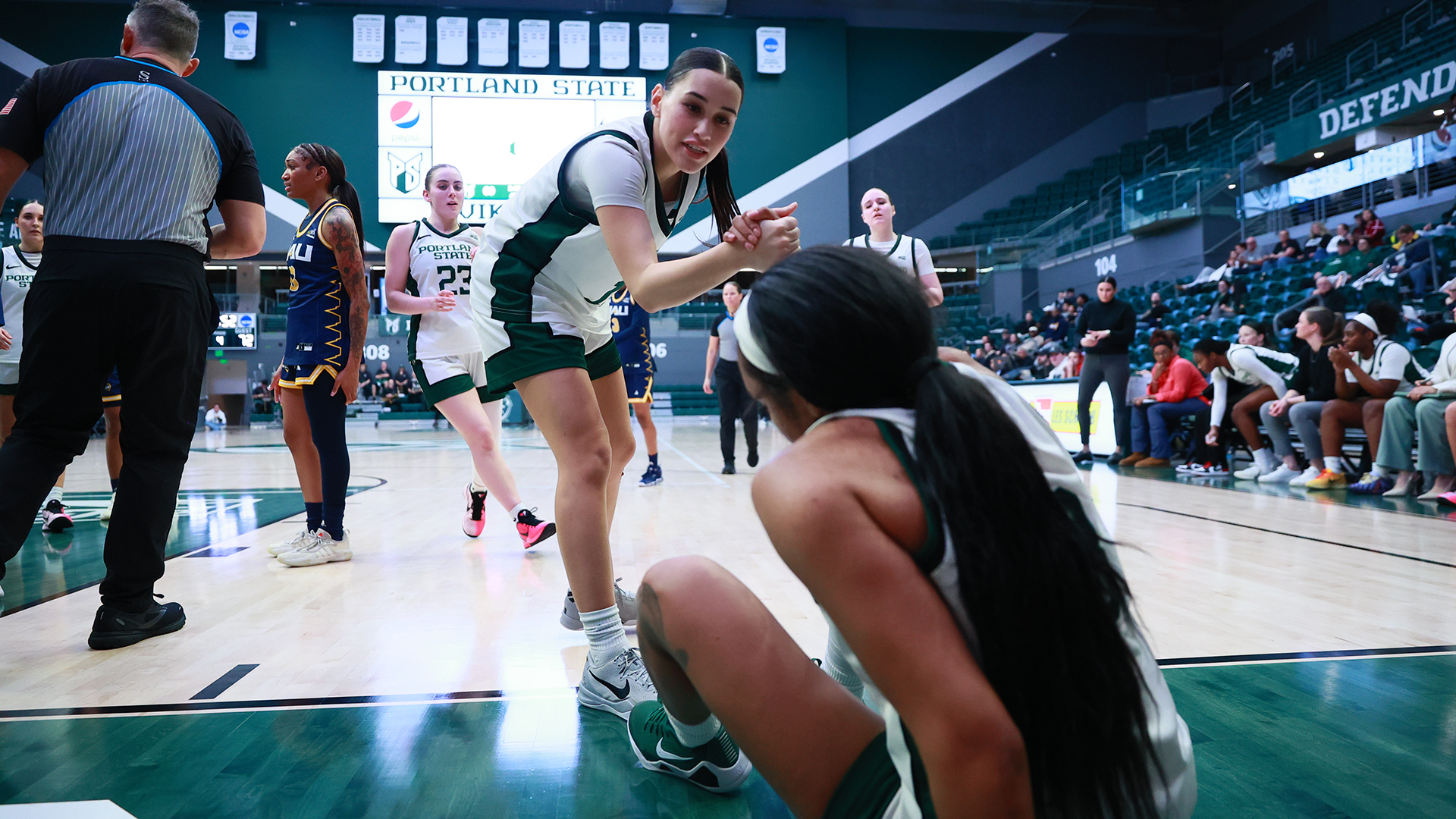 Portland State women's basketball player Laynee Torres-Kahapea helps up a teammate during the Vikings. 