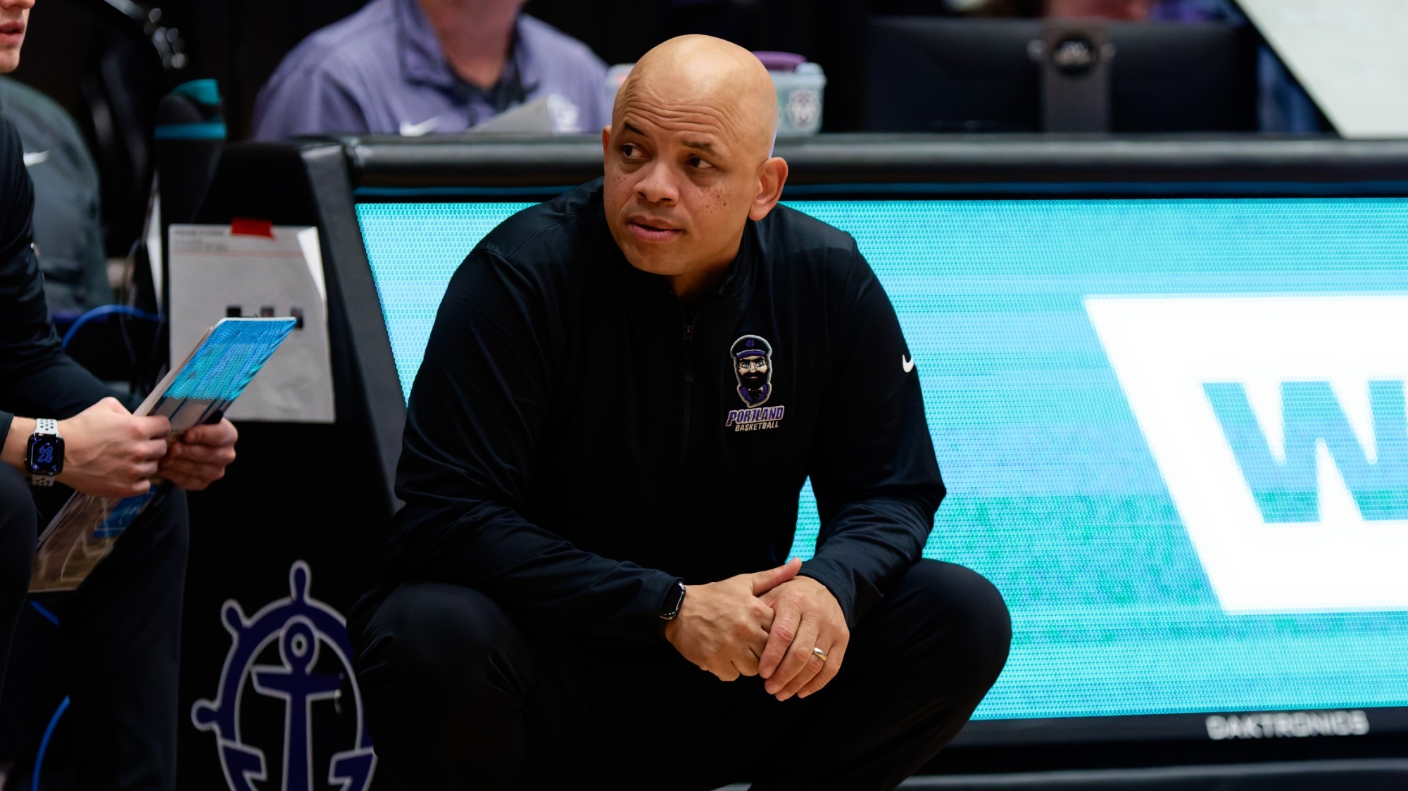 Coach Shantay Legans crouches on the sidelines during a Portland home game.