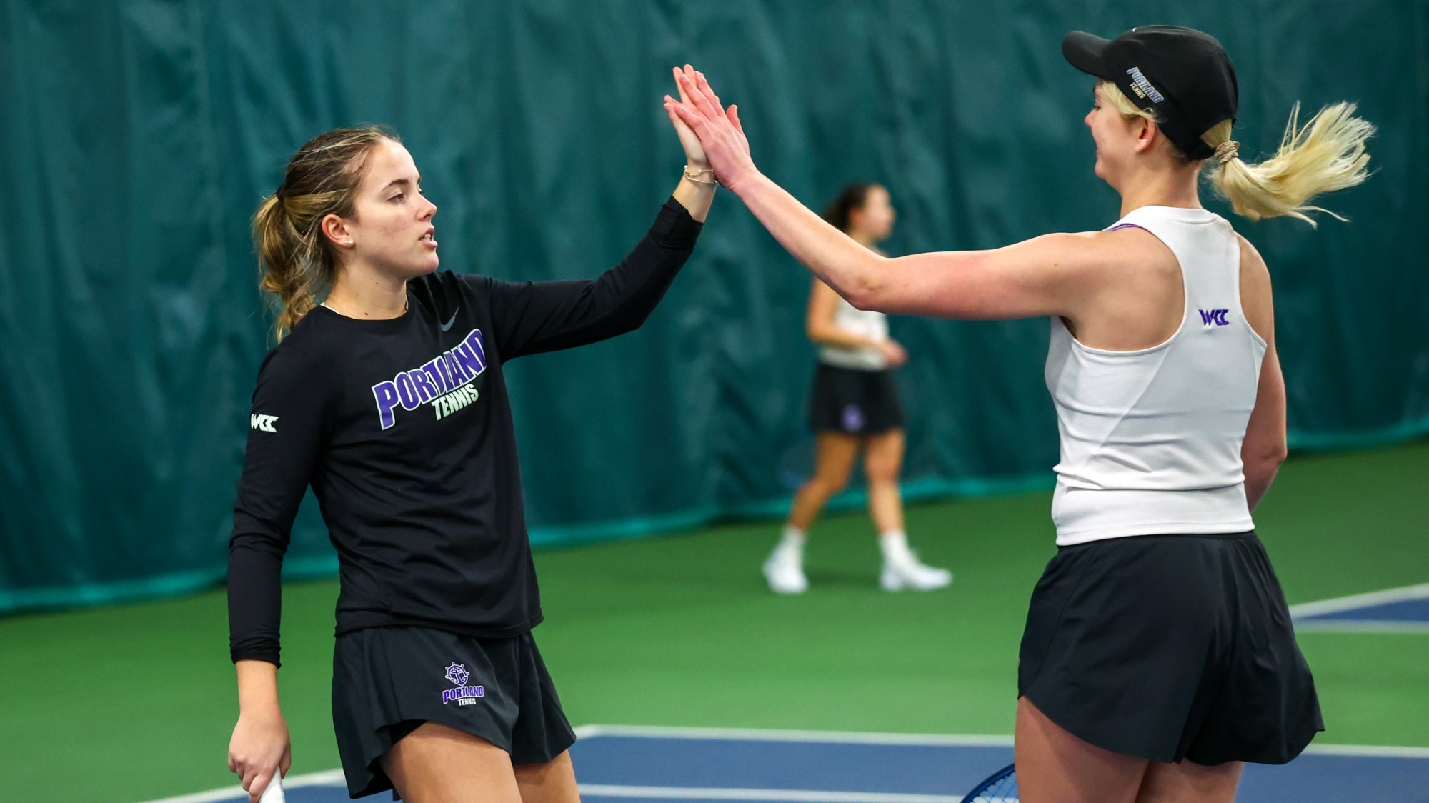 Nadine Arbaizar Martinez and Meagan Pearson celebrate a doubles point won at Stonehill College.