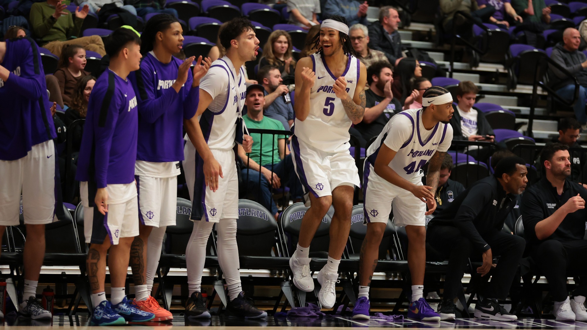 Portland men's basketball's bench celebrates during a home game against Santa Clara.