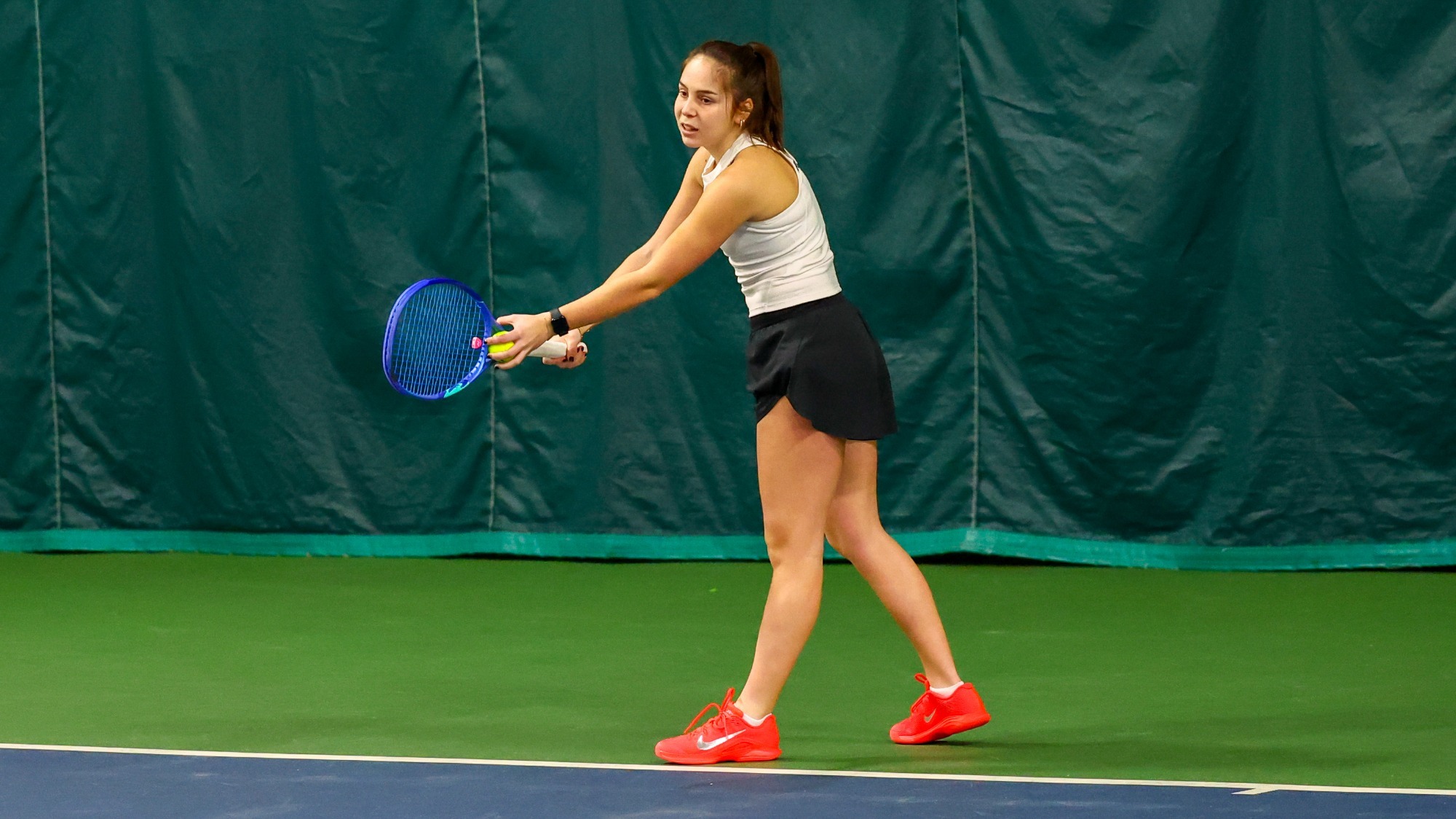 Alaia Rubio Perez goes into a serve motion during a singles match.