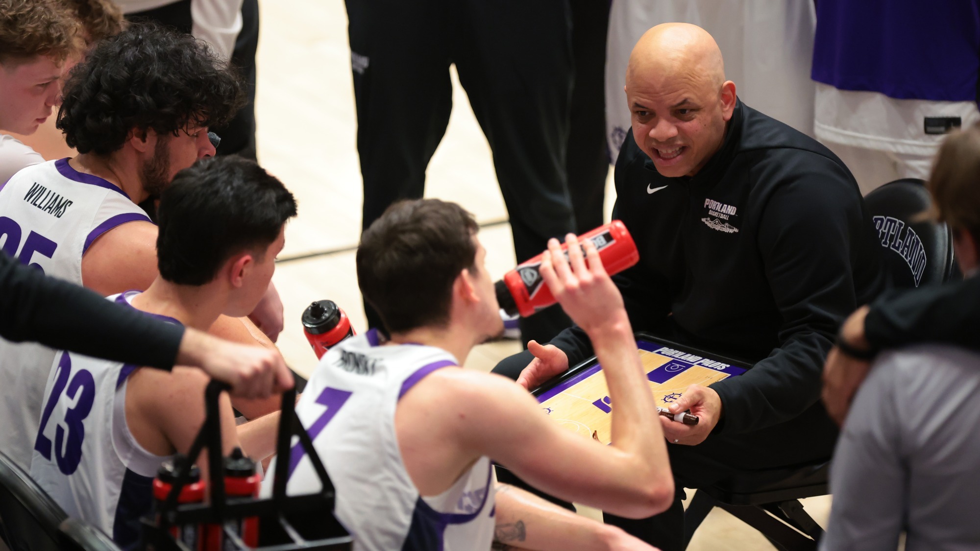 Portland men's basketball huddles during a timeout as Coach Shantay Legans draws up a play.