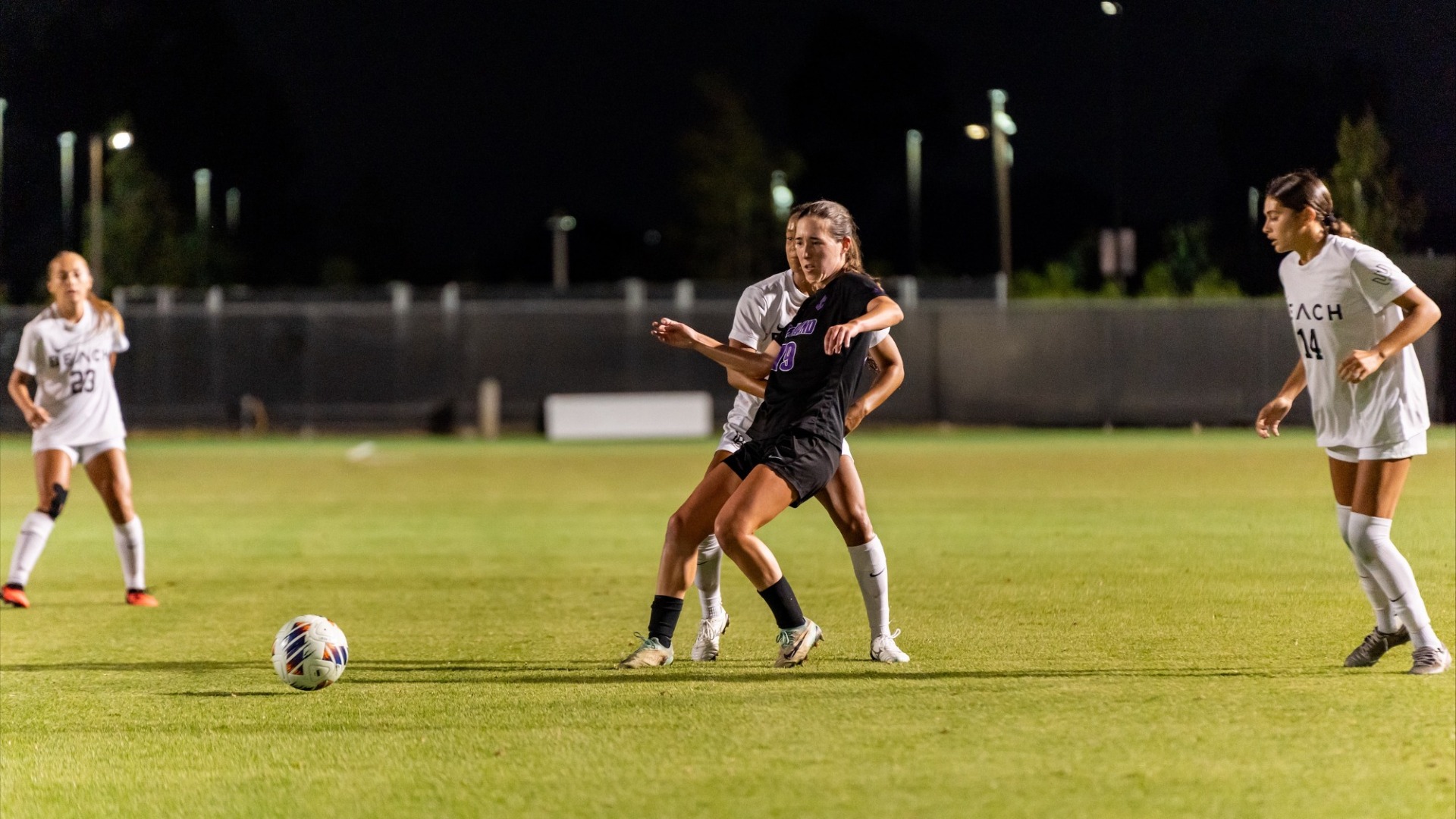Eli Rapp leans on a Long Beach State player while passing the ball.