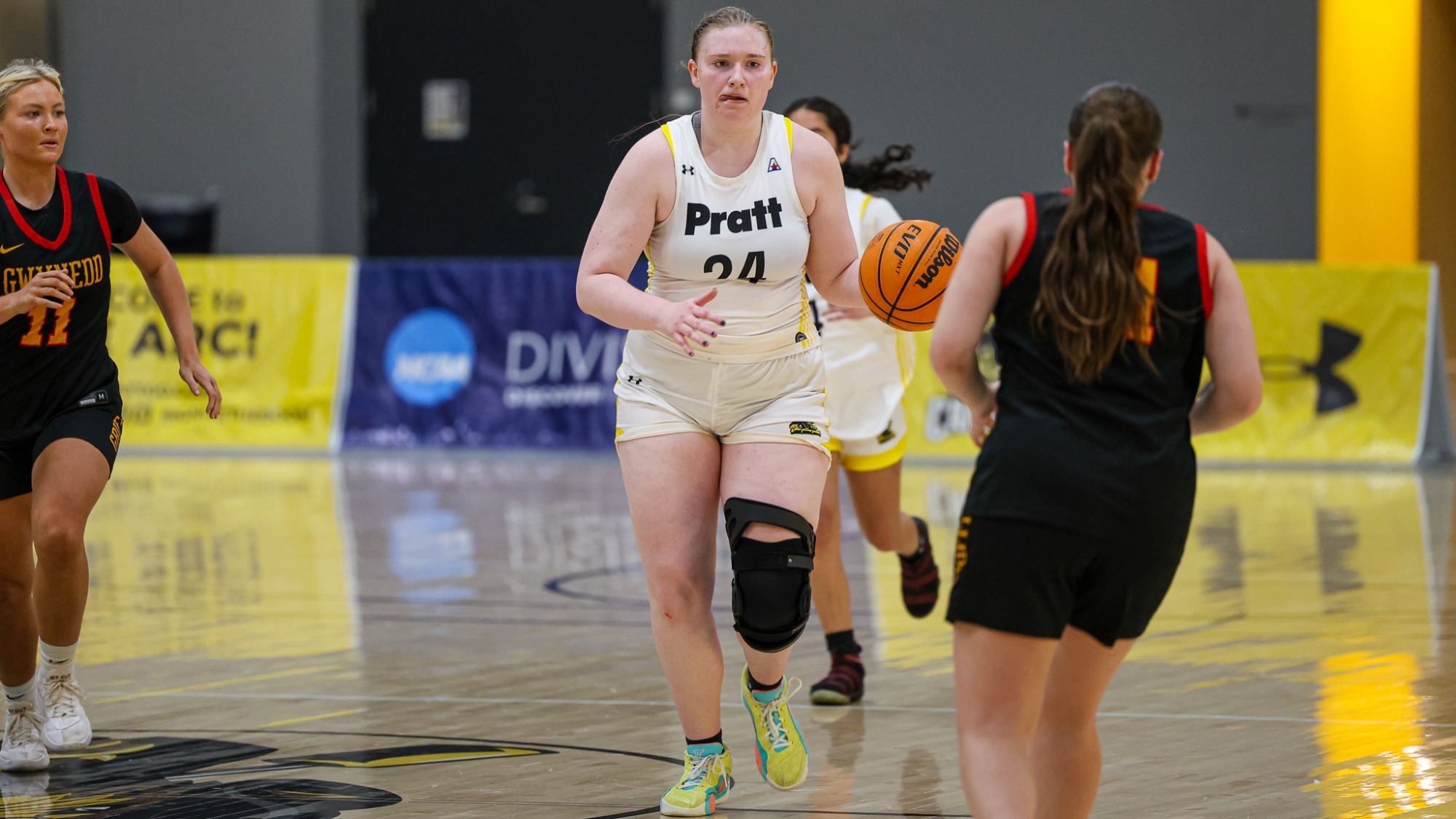 Emily Carlson dribbles at midcourt surrounded by several defenders