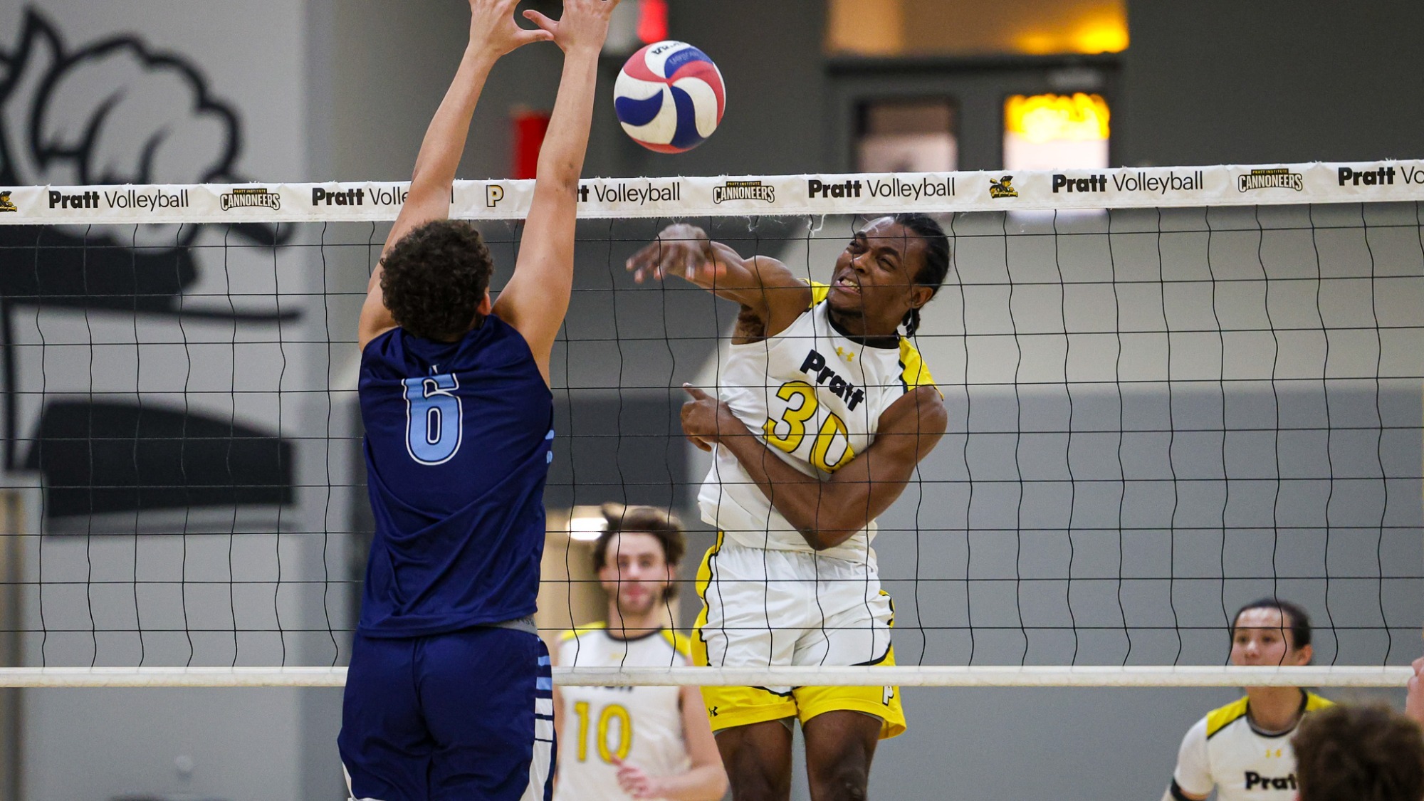 Morvens Regis spikes a ball with a defender trying to block 