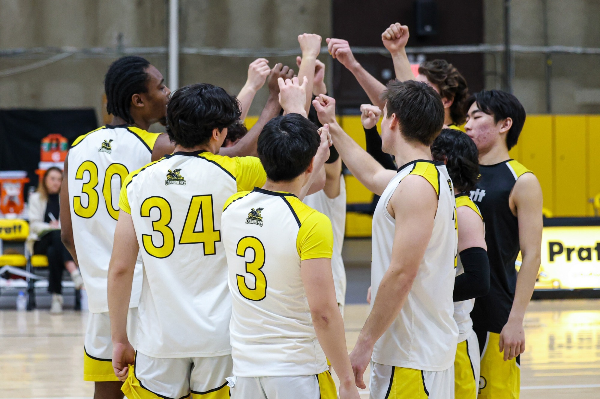 The men's volleyball team puts their hands in the middle prior to the start of the match.