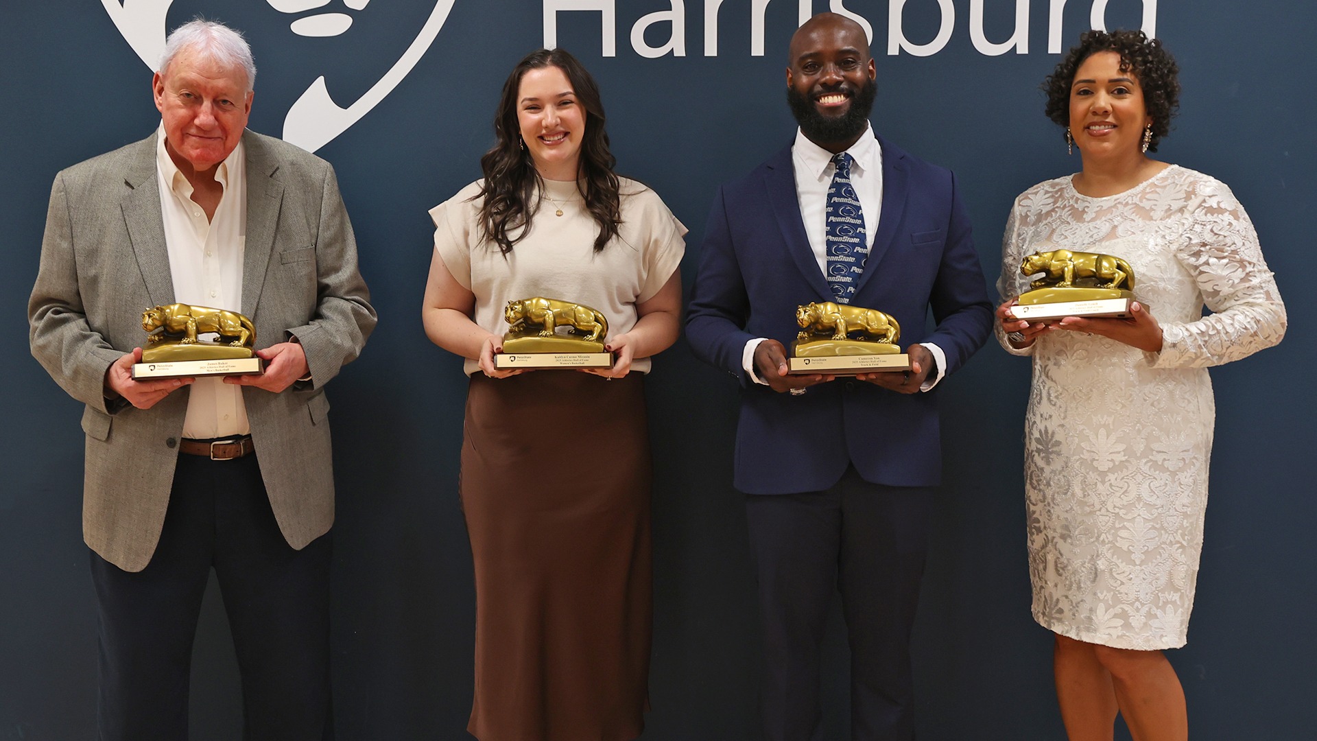 jim baker, kaitlyn carmo mizanin, cameron yon and danielle lynch pose with their gold lion shrines before the 2025 athletics hall of fame ceremony