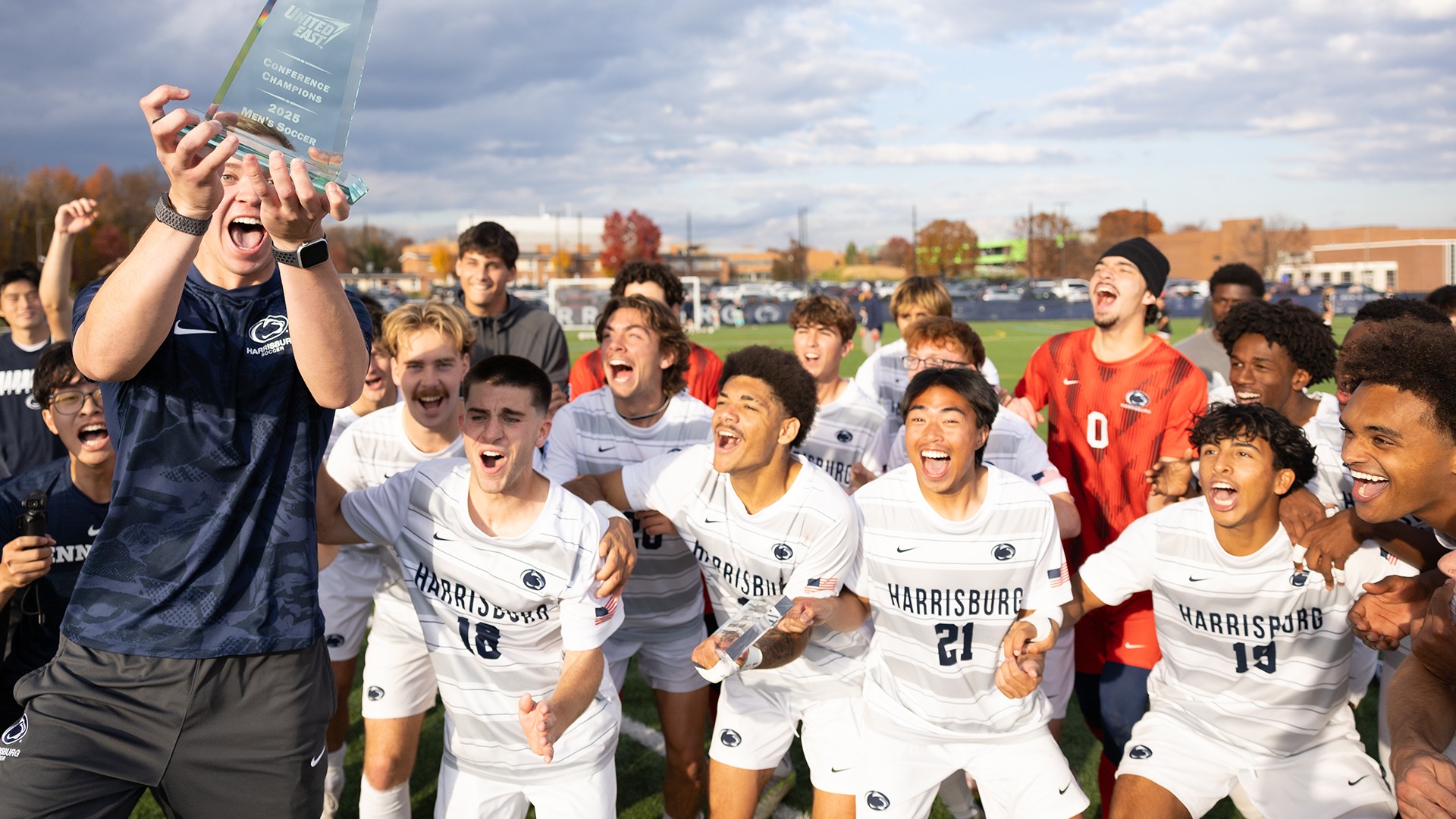 ethan smith holds the united east championship trophy while celebrating with teammates after winning the 2025 conference title