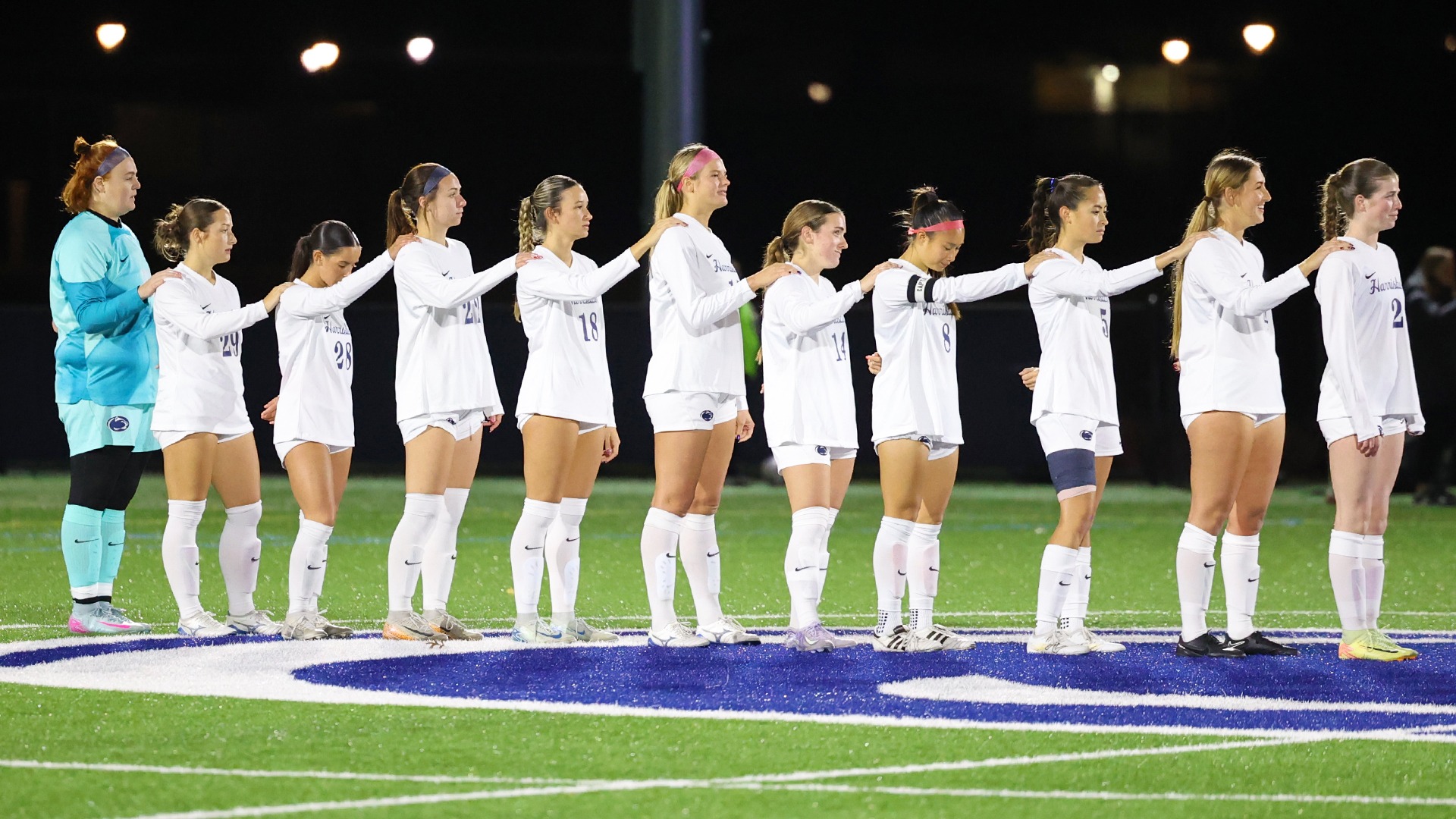 women's soccer players line up for the national anthem prior to a playoff game in 2025