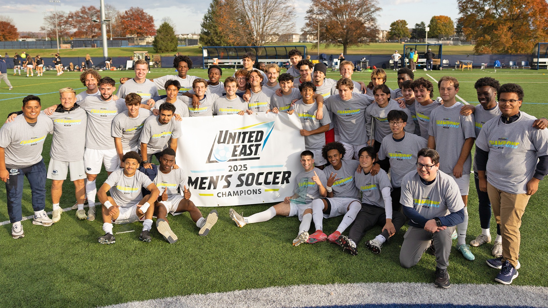 penn state harrisburg's men's soccer team poses with the 2025 united east championship banner