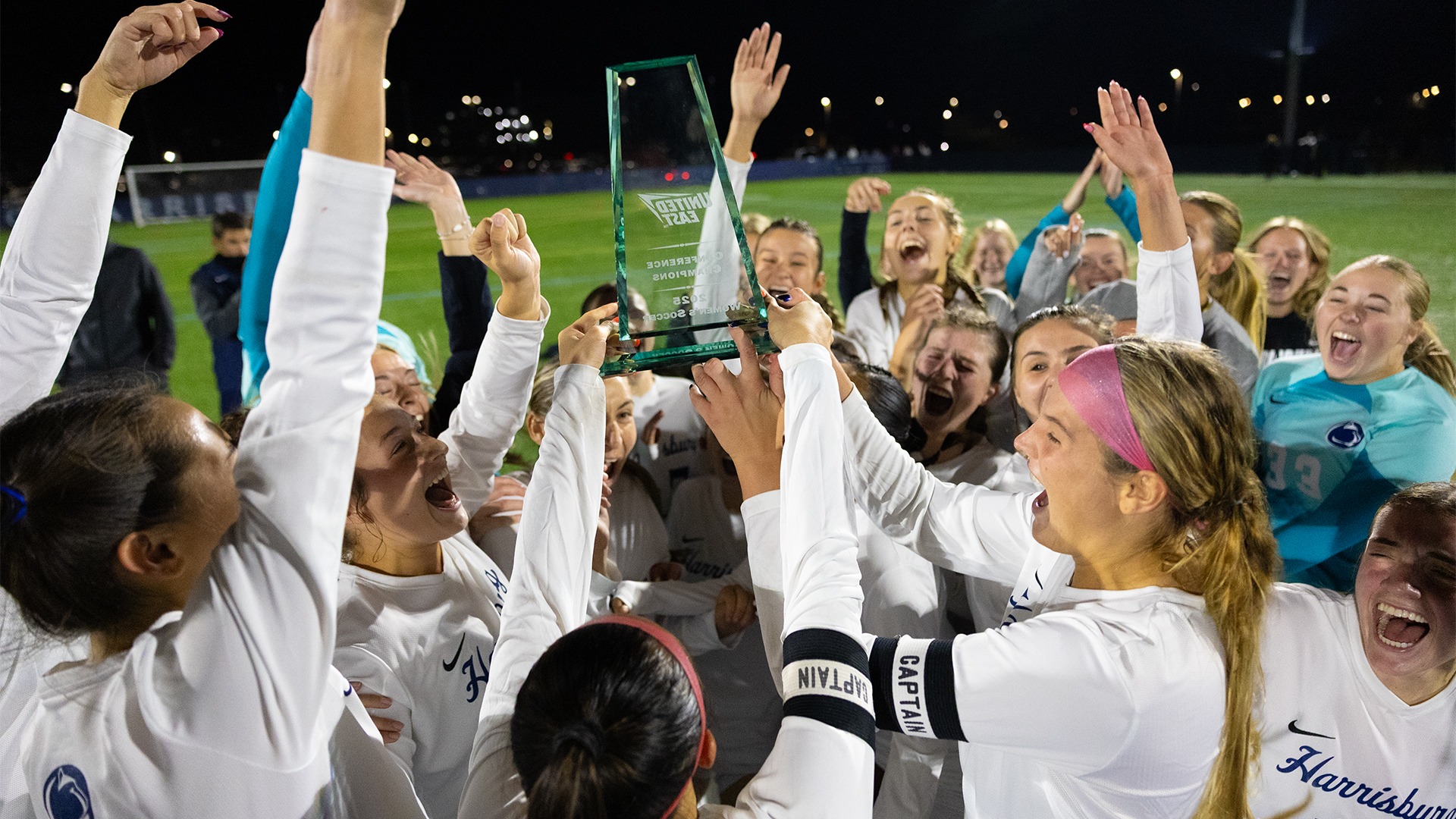 women's soccer players celebrate with the trophy after winning the united east championship in 2025