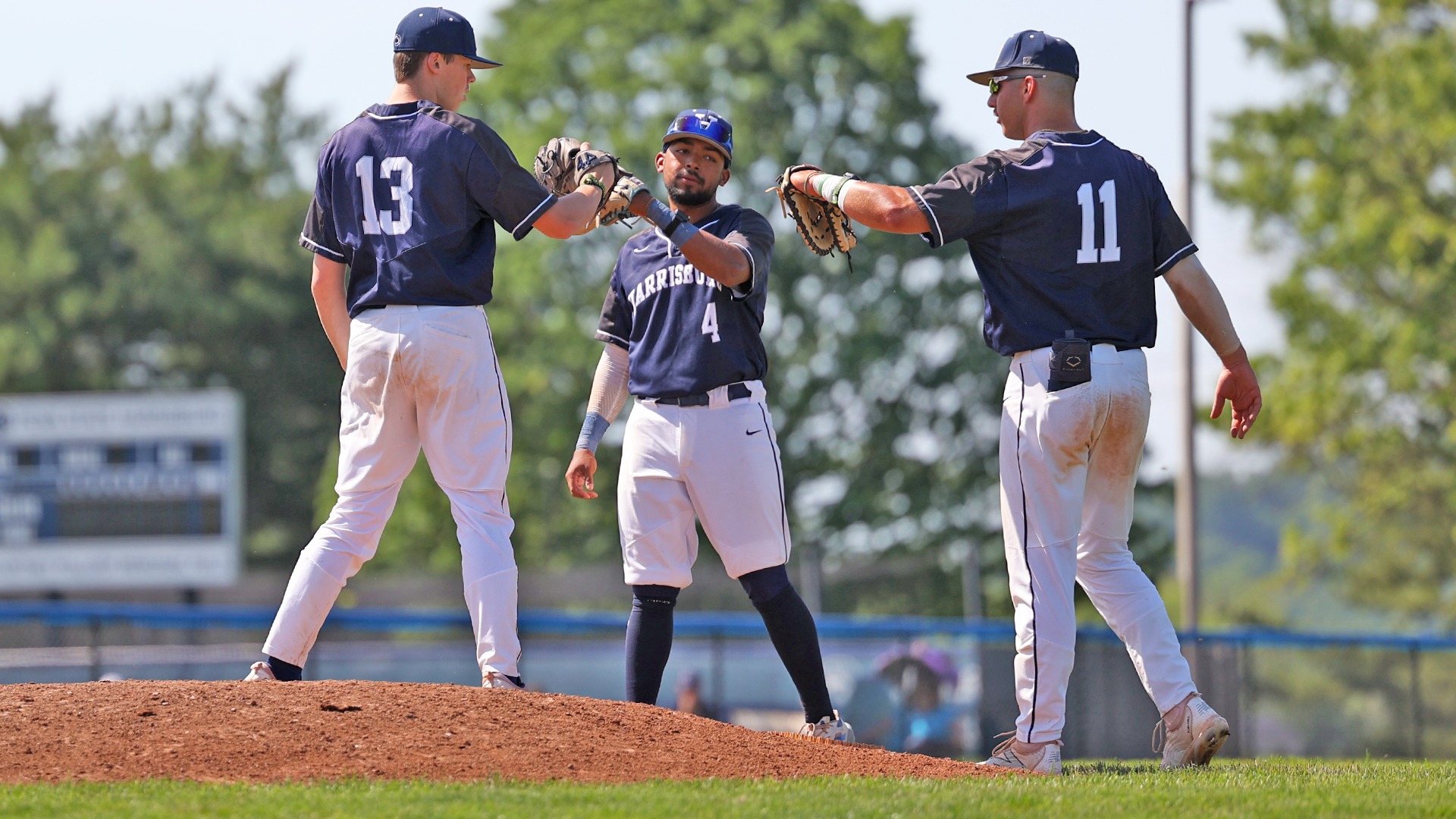 dylan sattazahn, alex ruiz and demetre koutras bump gloves behind the mound during an ncaa regional win over tcnj in 2025