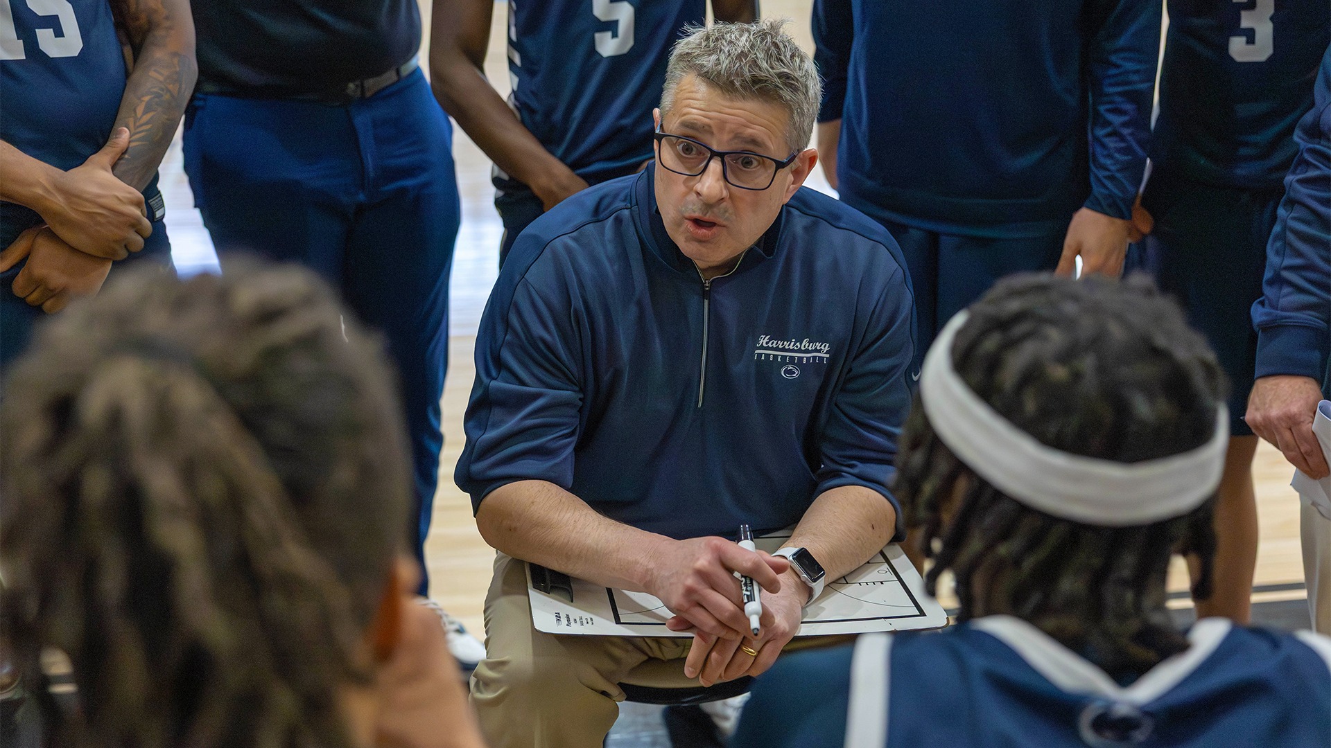 head coach don friday talks to men's basketball players in a huddle during the united east championship game at cairn