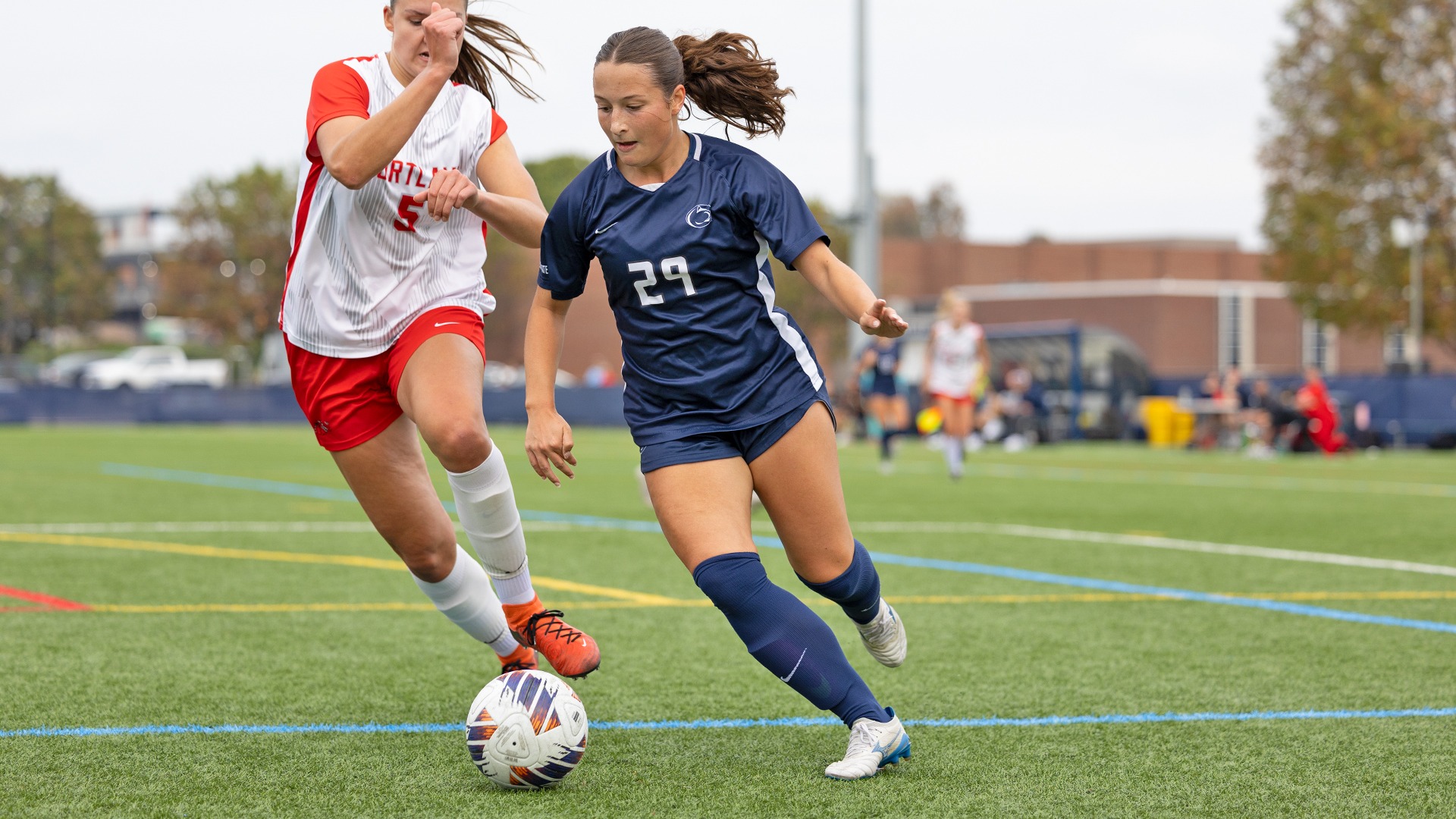 ava myers dribbles a ball past a defender near the end line during a game against cortland in 2025