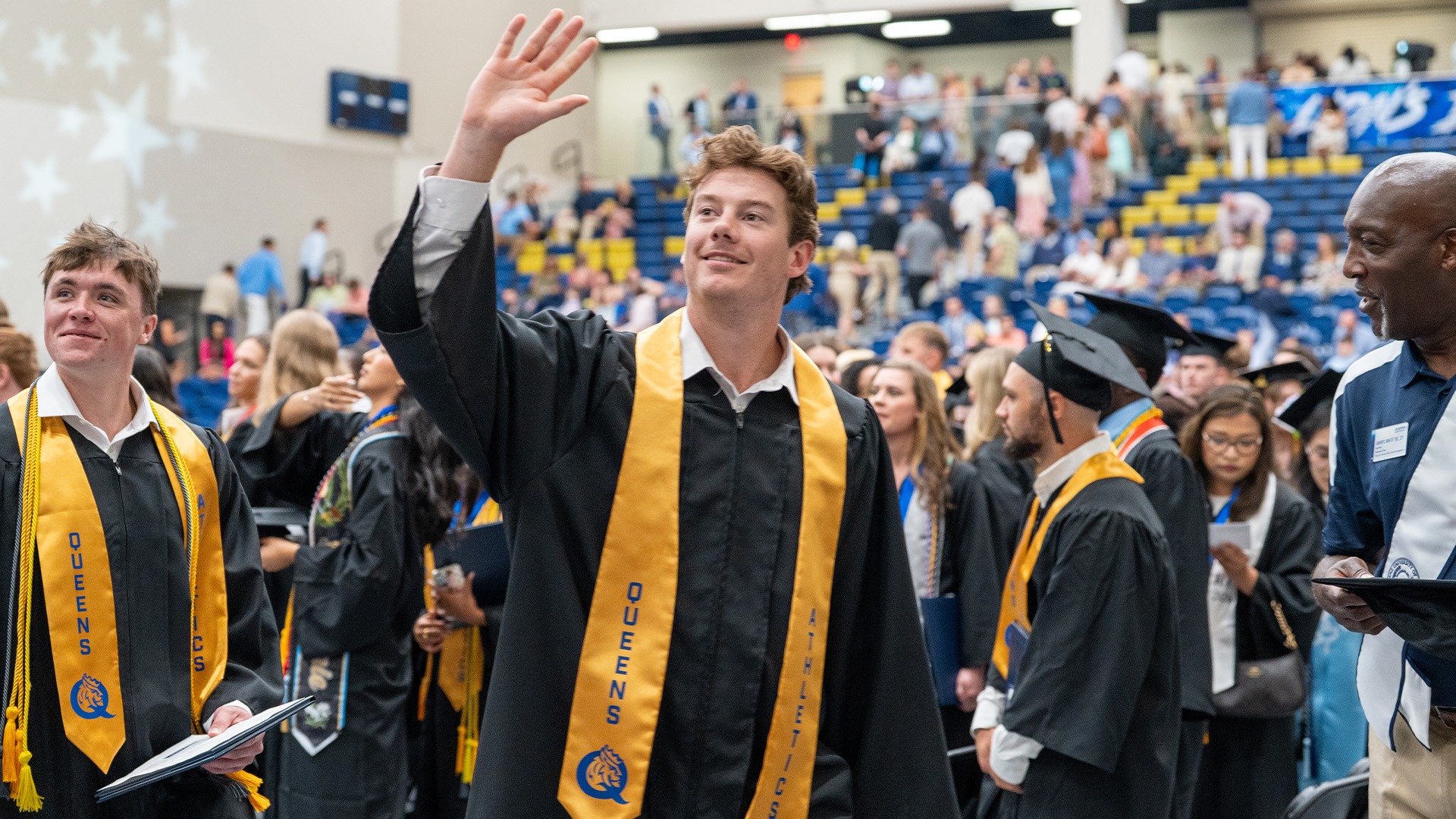Queens men's lacrosse student-athlete Michael White waving to the crowd at 2026 Commencement
