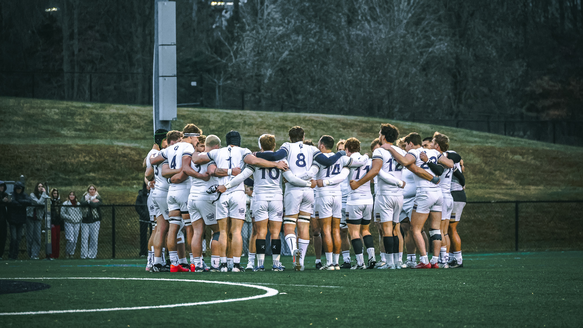 Men's rugby in huddle at Dickson Field