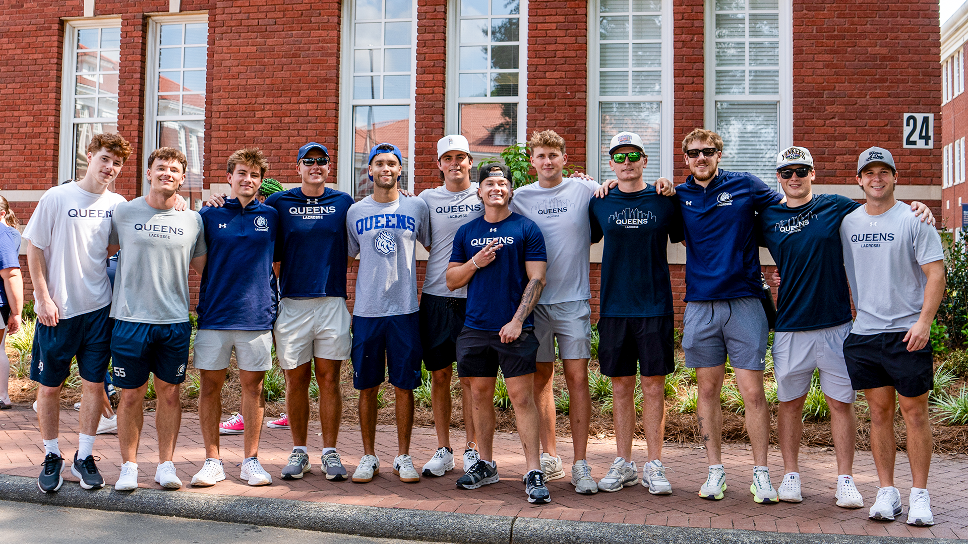 Men's lacrosse players pose for picture on campus on new student move-in day. 