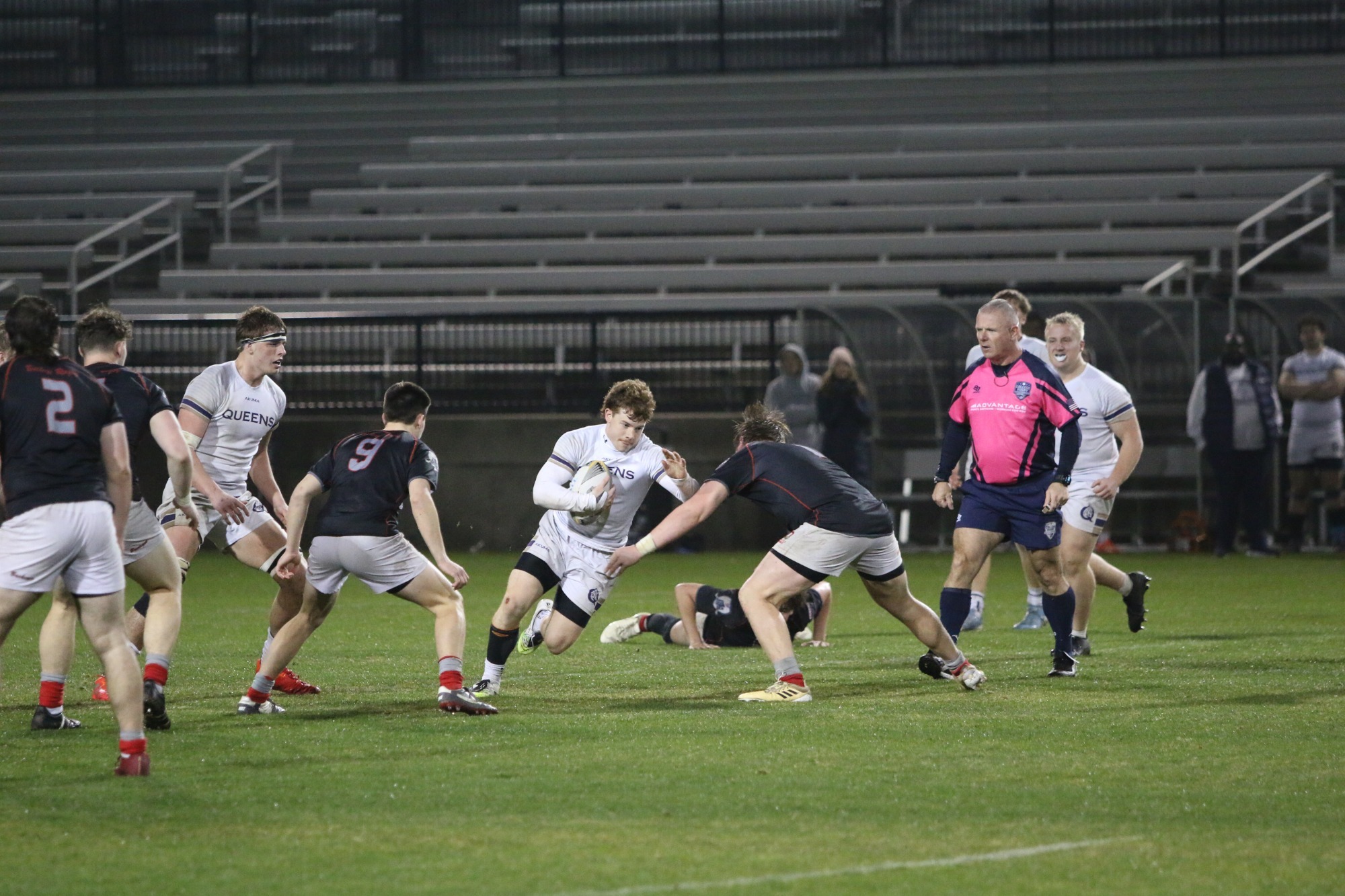 Men's rugby player races up the field through traffic.