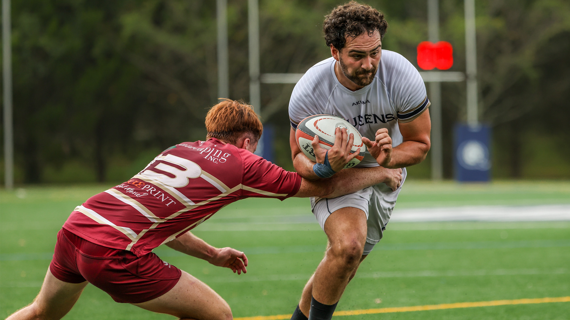 Men's rugby player shaking off the defender.