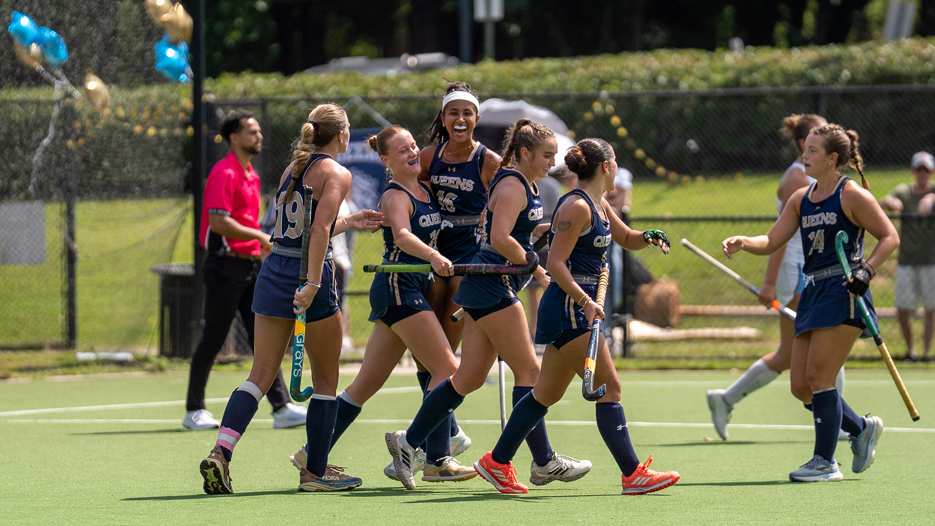 Queens field hockey team celebrating after a scored goal.