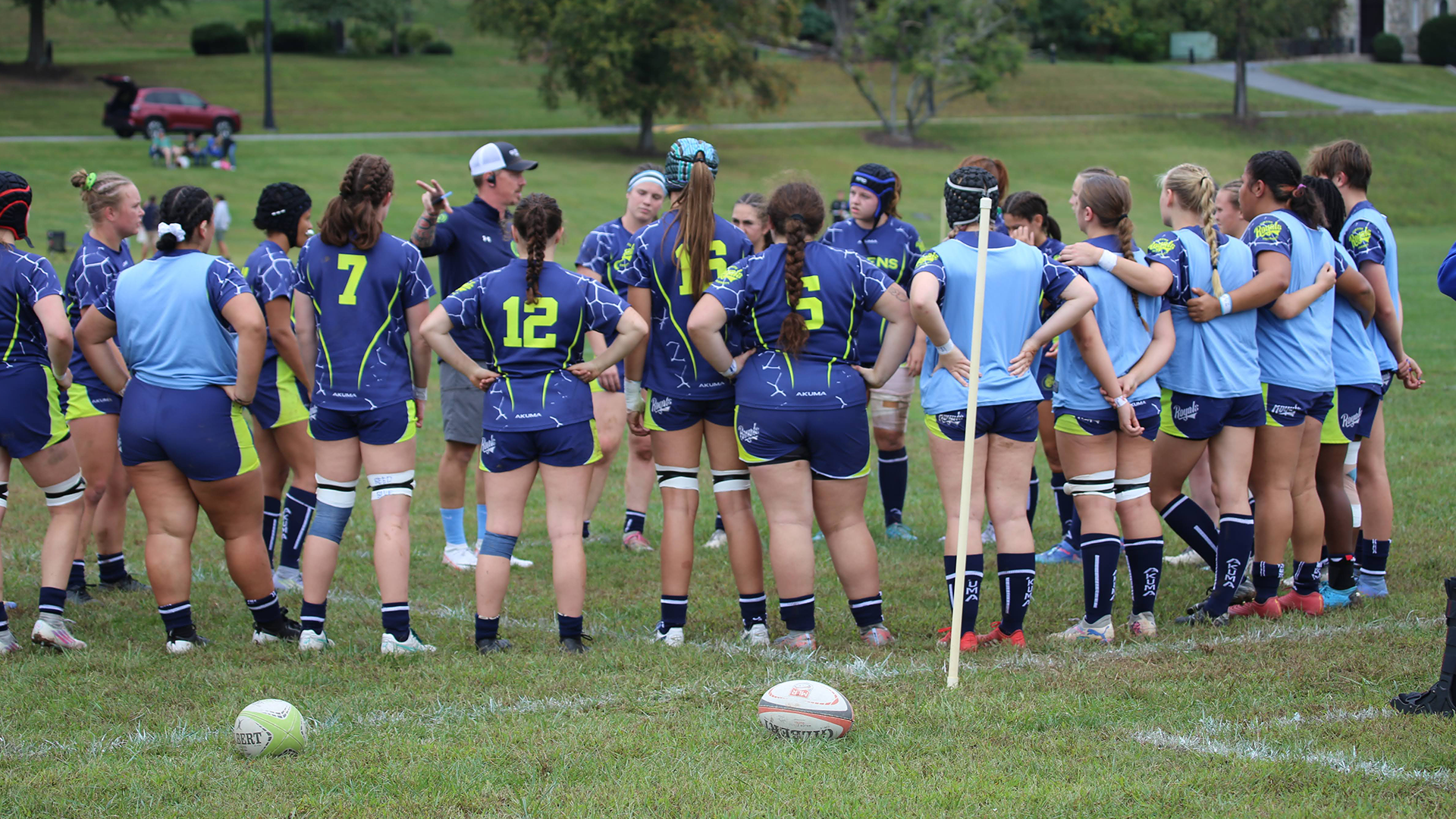 Women's rugby in sideline huddle.