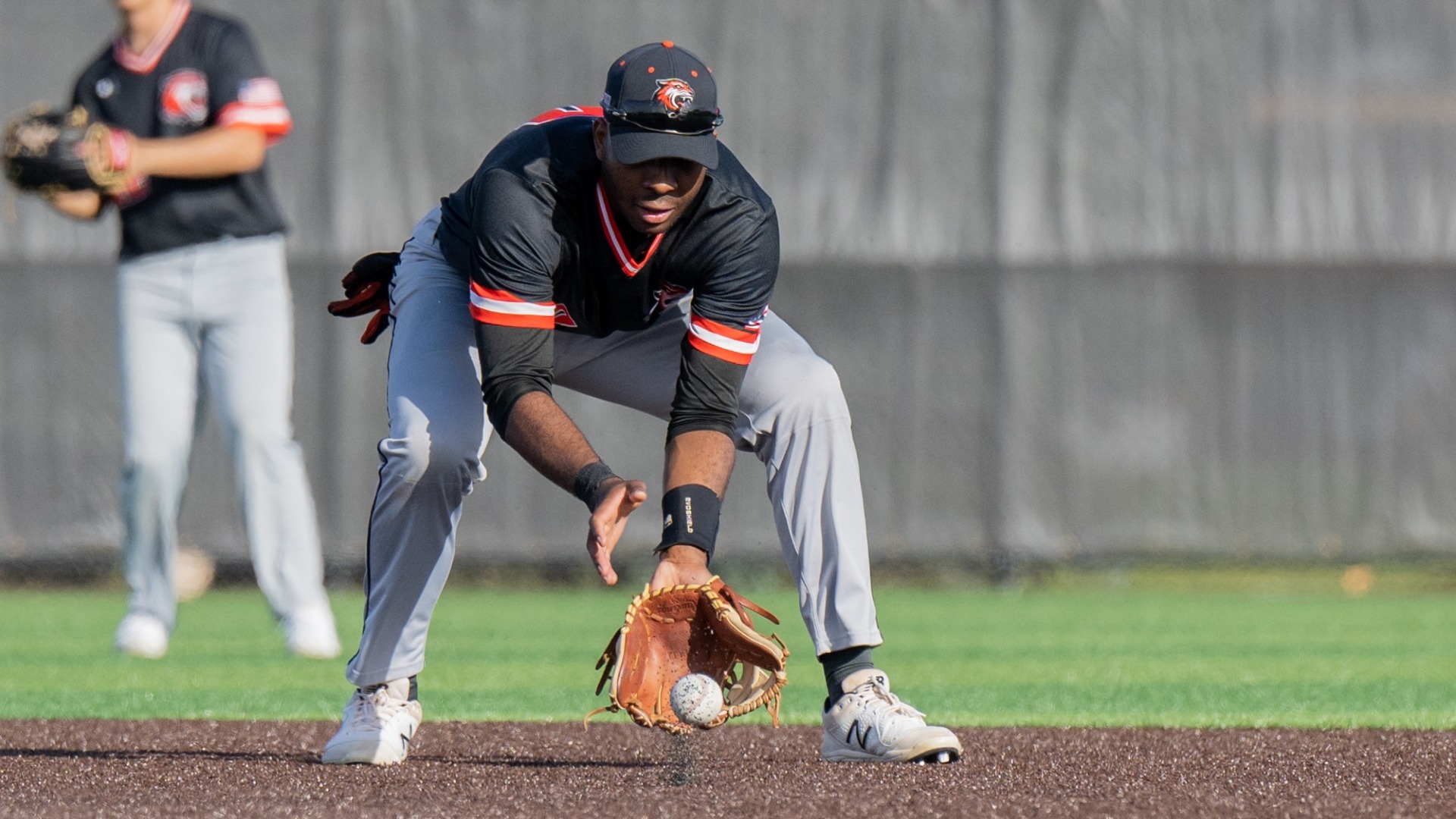 an RIT baseball player fields a ball