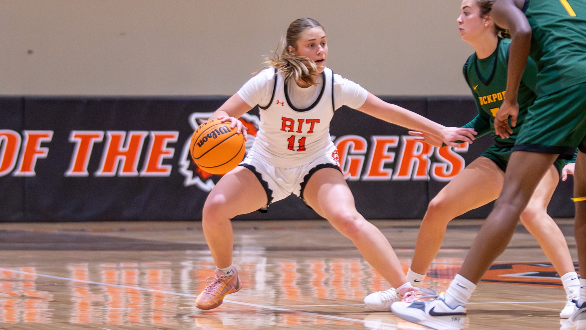 A women's basketball player tries to beat a pair of defenders