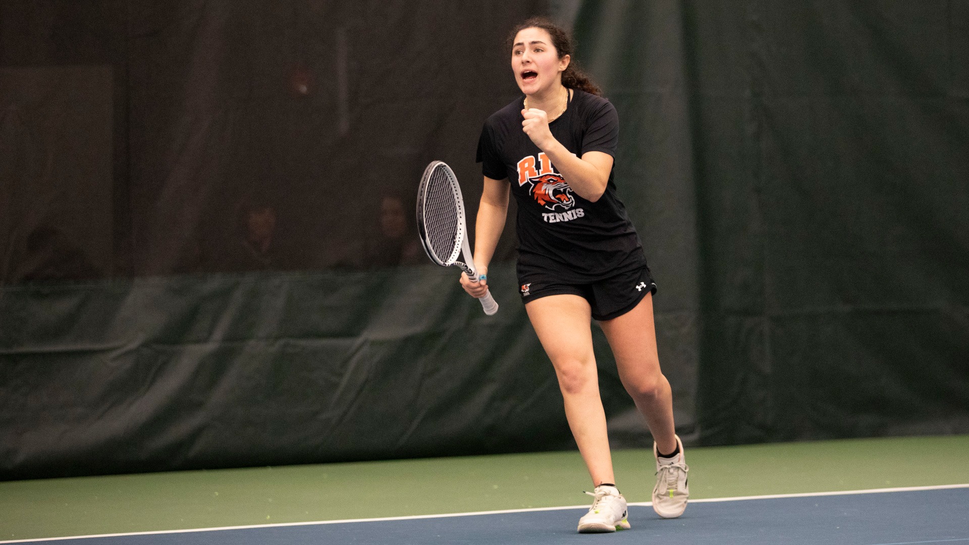 A women's tennis player celebrates winning a point