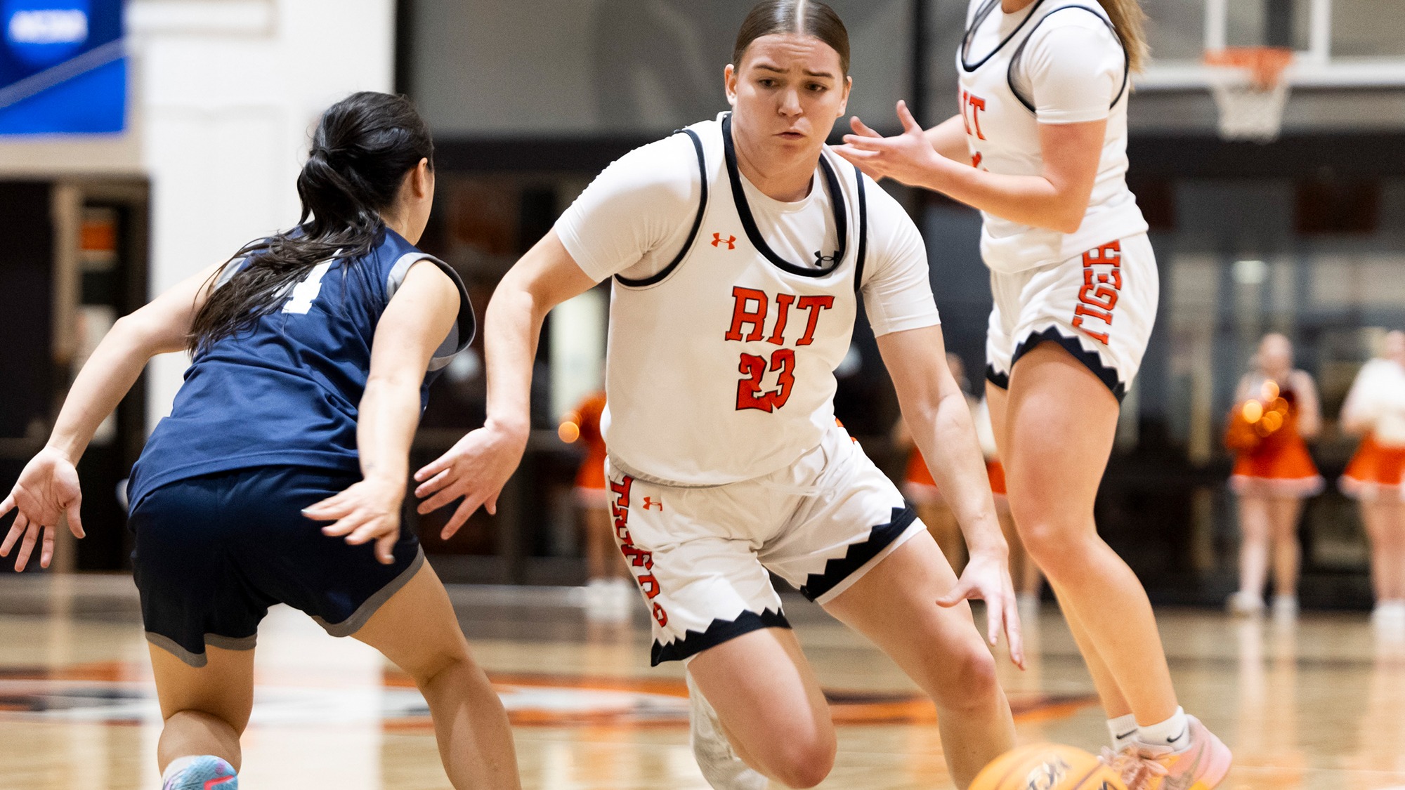 a women's basketball player dribbles past a defender in a game for Rochester Institute of Technology