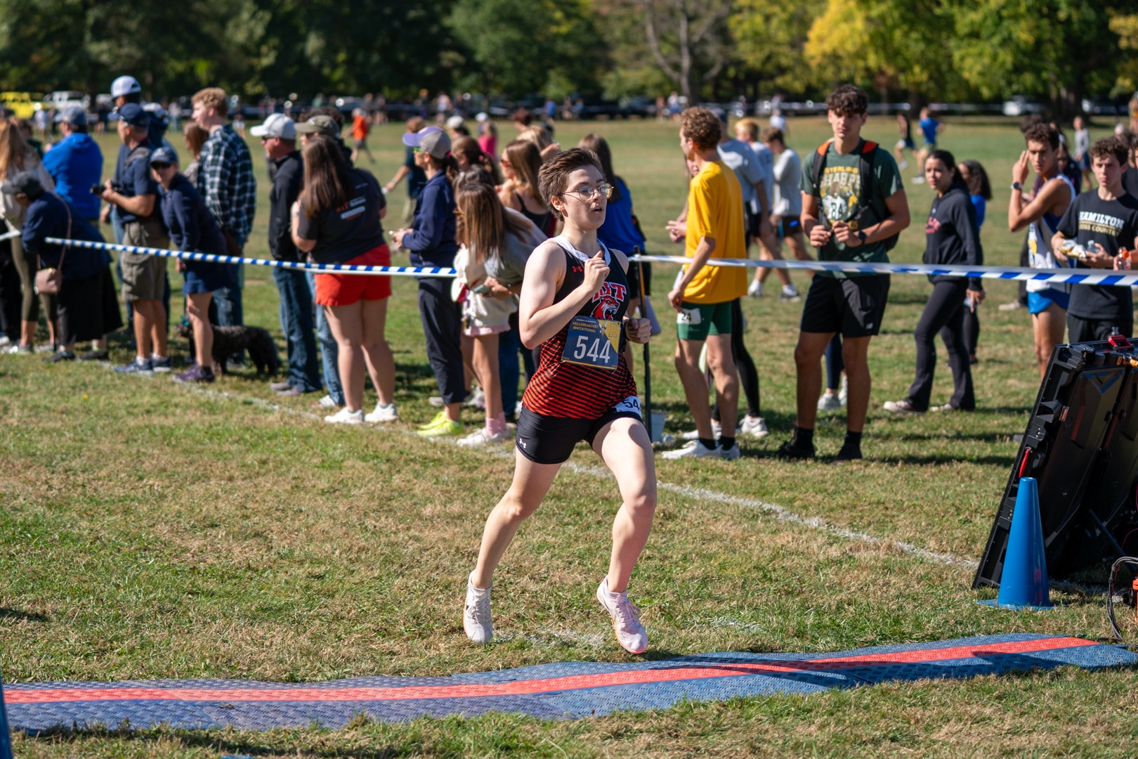 A women's cross country runner for Rochester Institute of Technology crosses the finish line in a race at Genesee Valley Park
