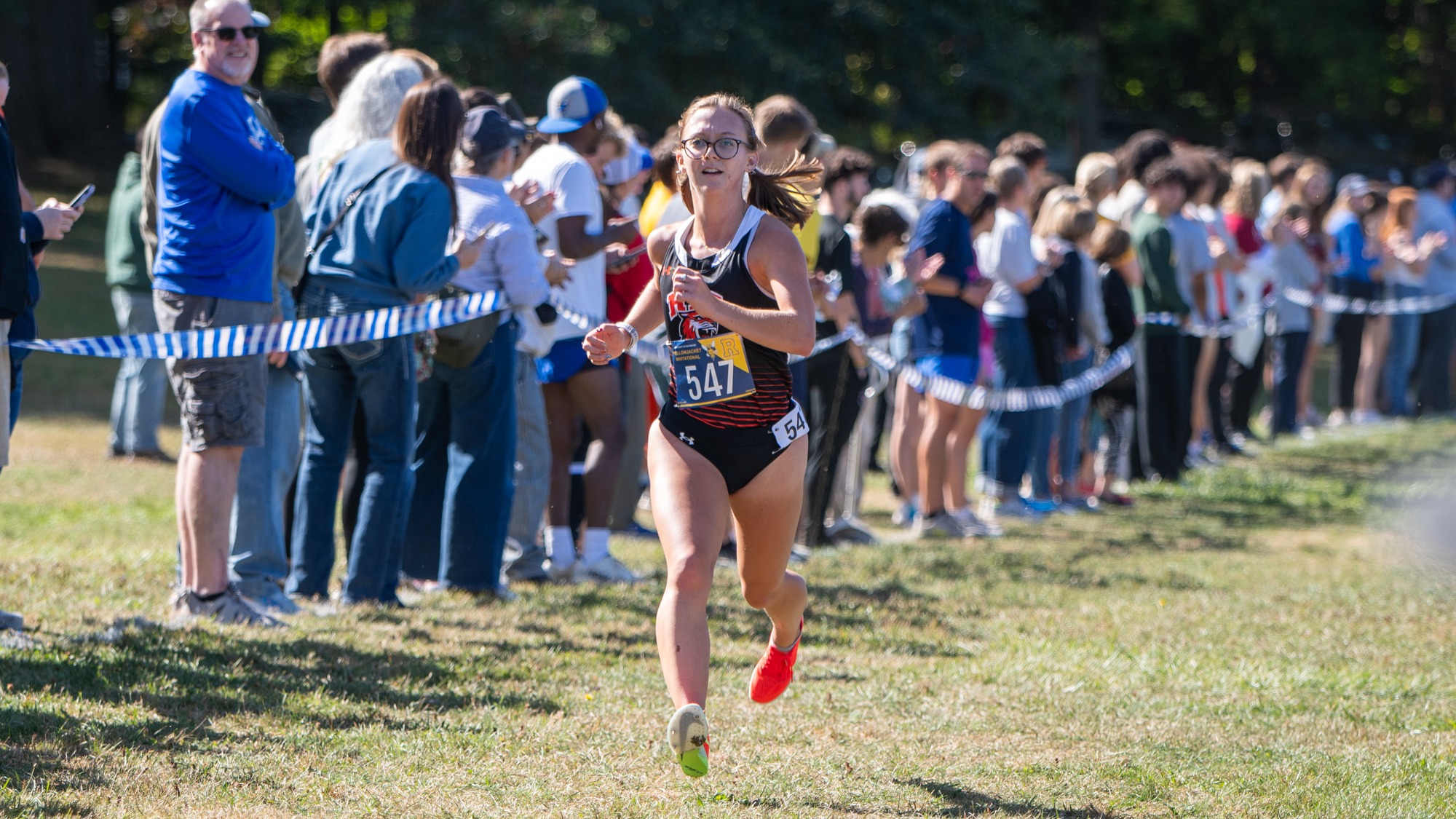 A women's cross country runner nears the finish line in a race for Rochester Institute of Technology