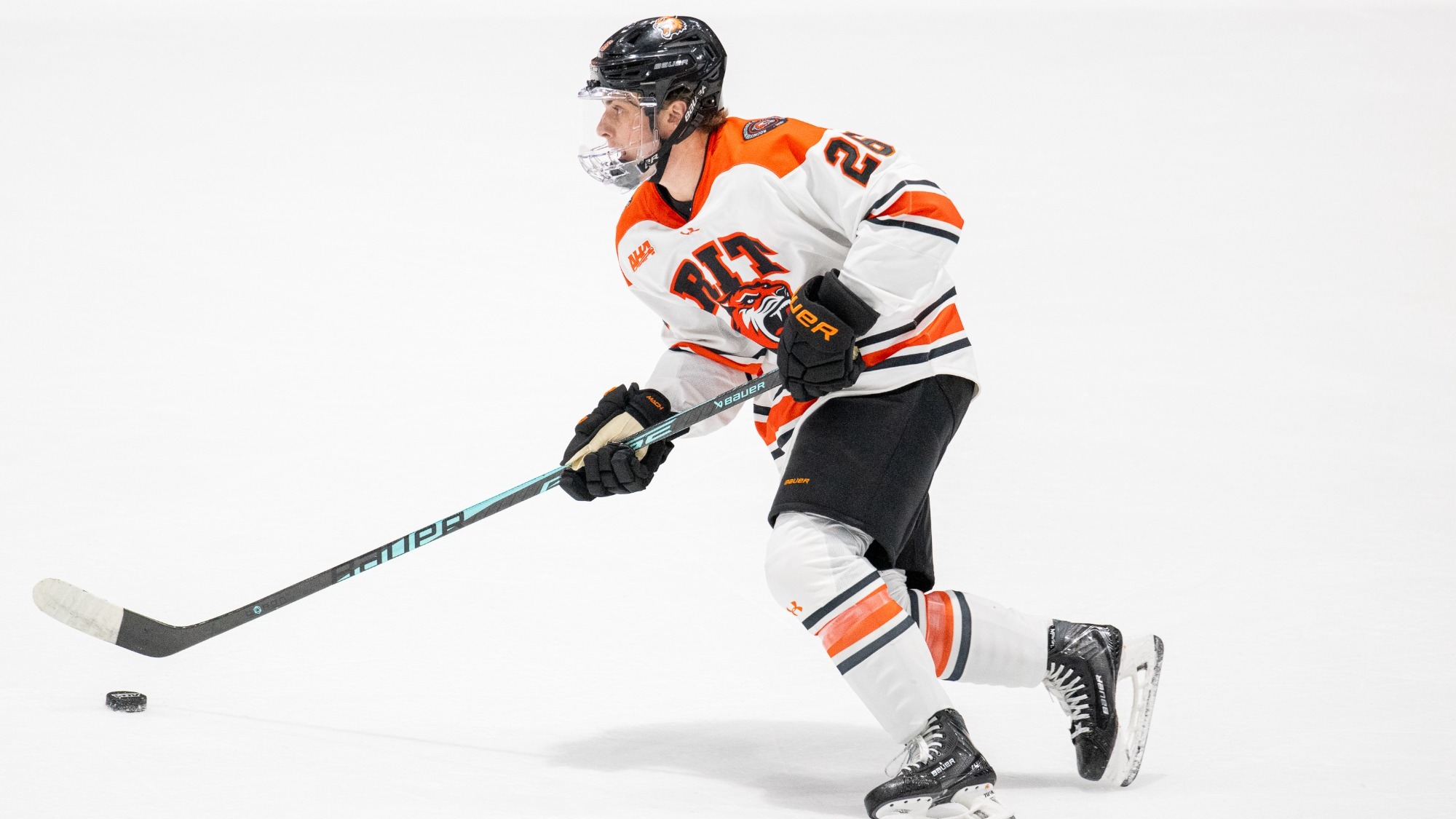 a men's hockey player skating with the puck