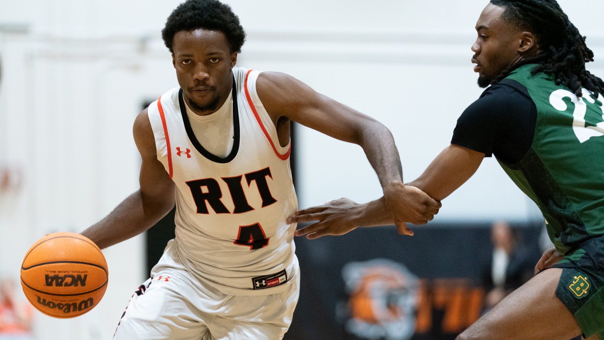 A Rochester Institute of Technology men's basketball player dribbles past a defender in a game against Brockport on December, 2, 2025