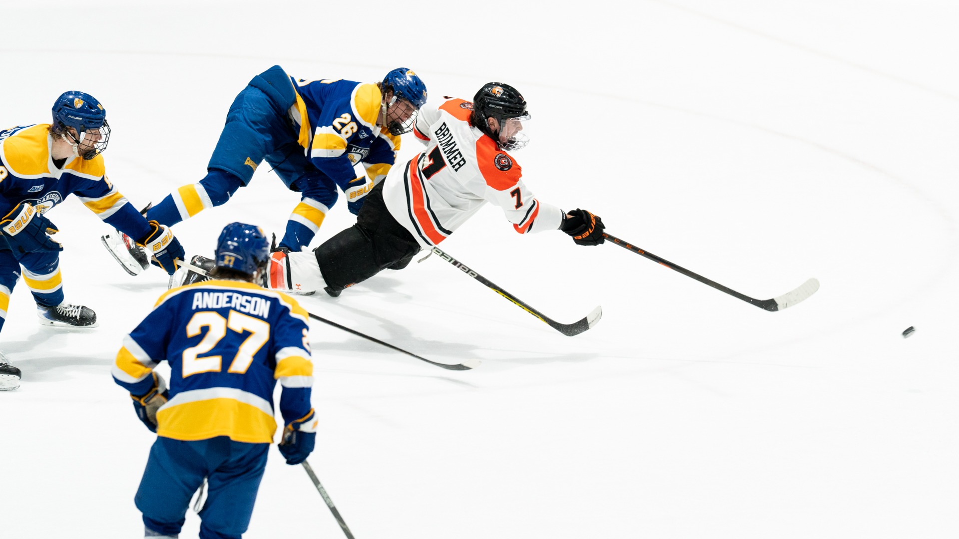a men's hockey player dives to take a shot 