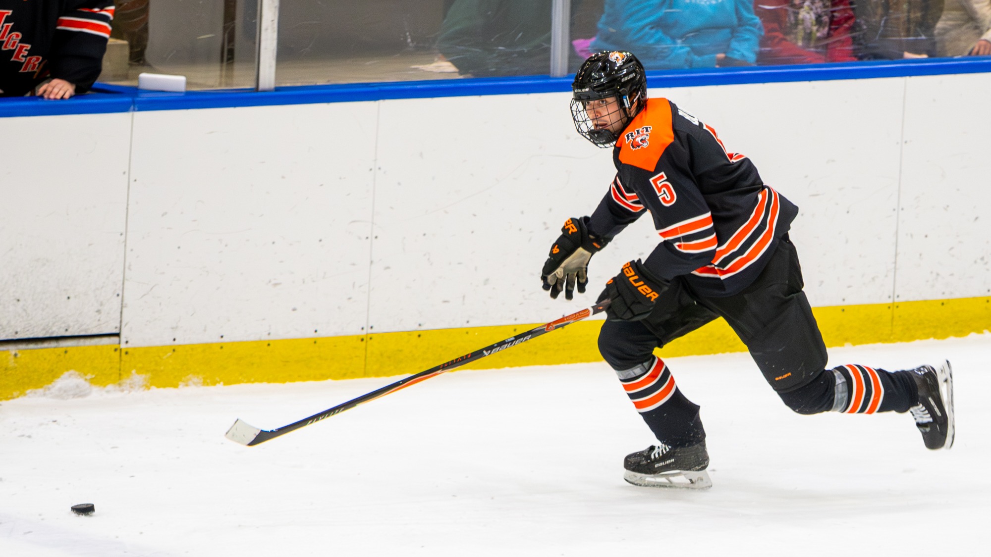 a men's hockey player skating with the buck