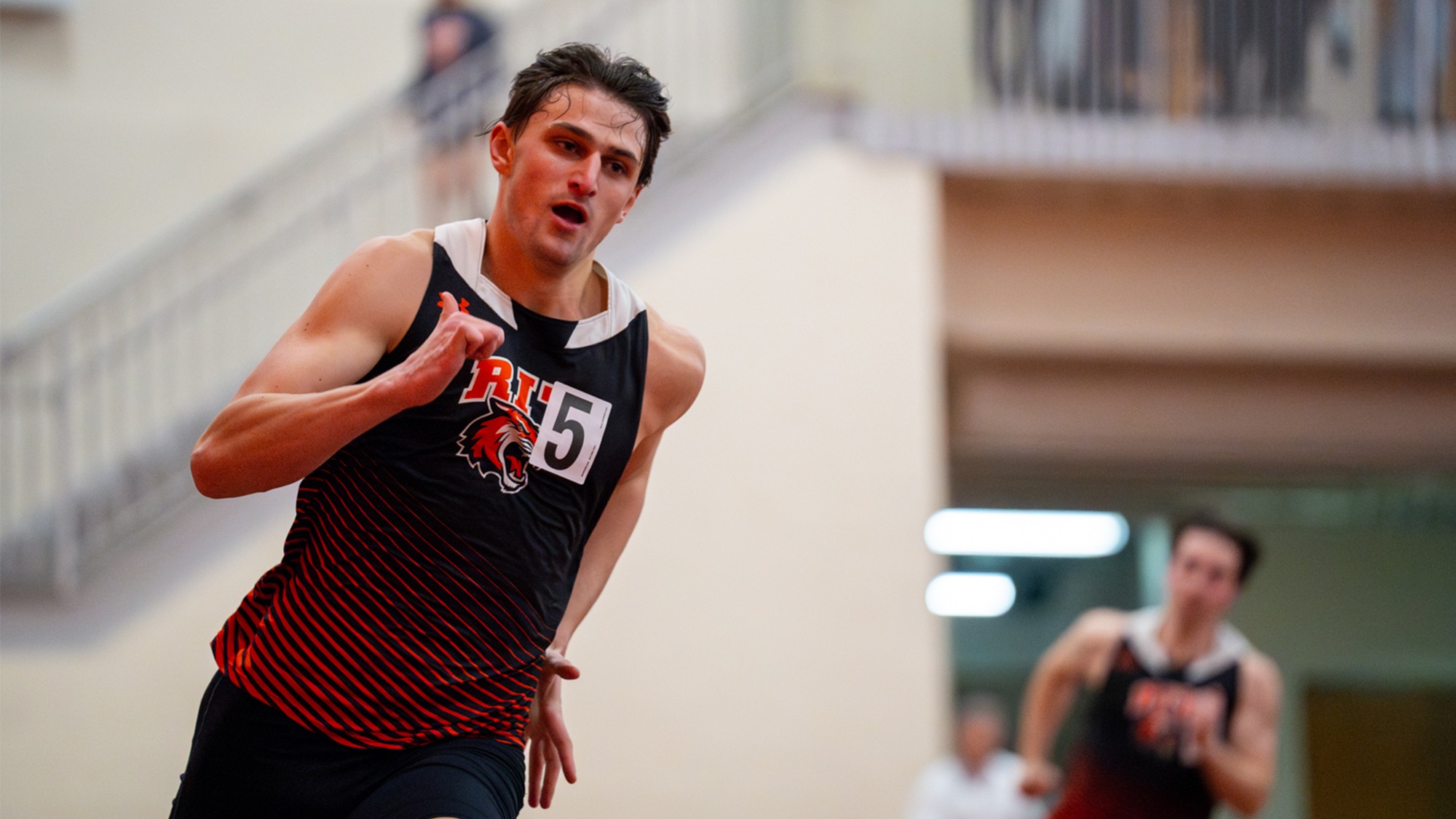 a men's sprinter competes in a race for Rochester Institute of Technology