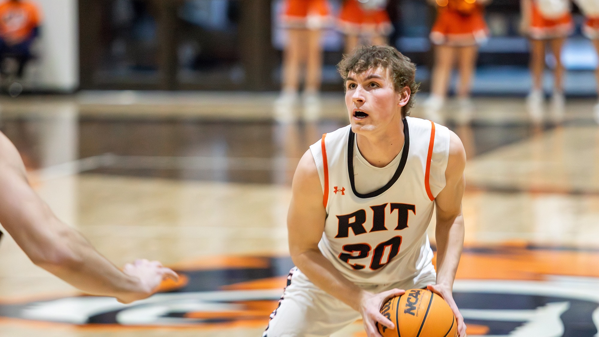 a men's basketball player for Rochester Institute of Technology looks to make a move with the ball