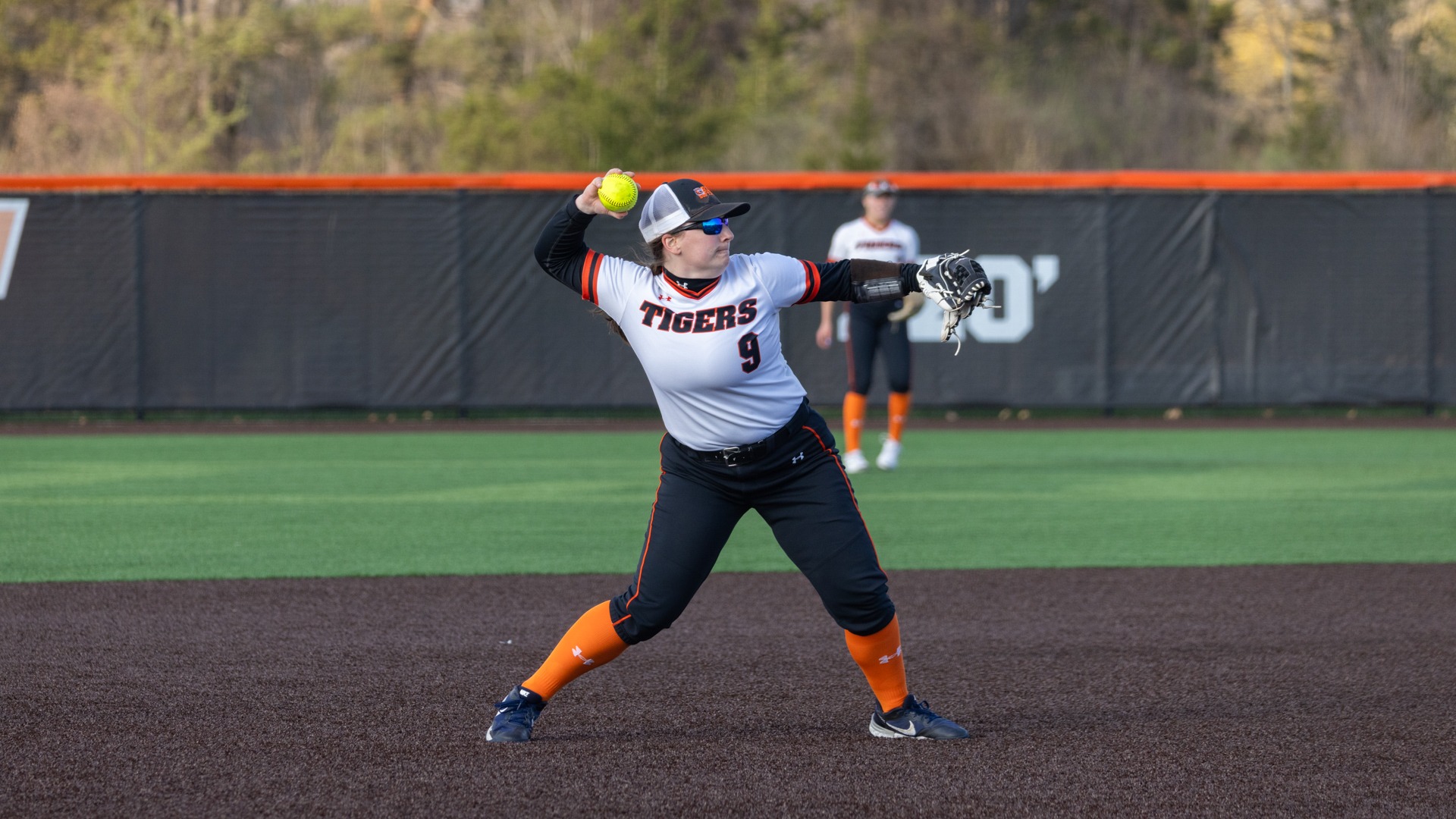 a softball player throwing the ball across the infield