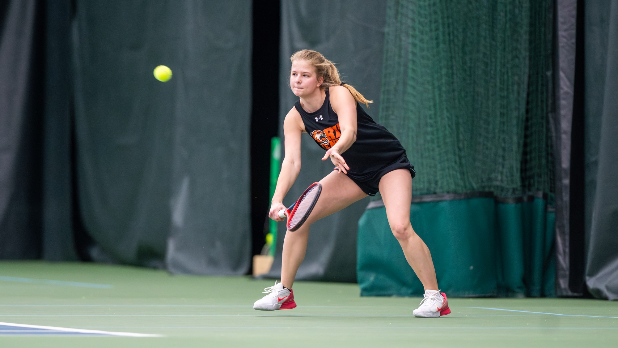 A women's tennis player returning a ball using her forehand