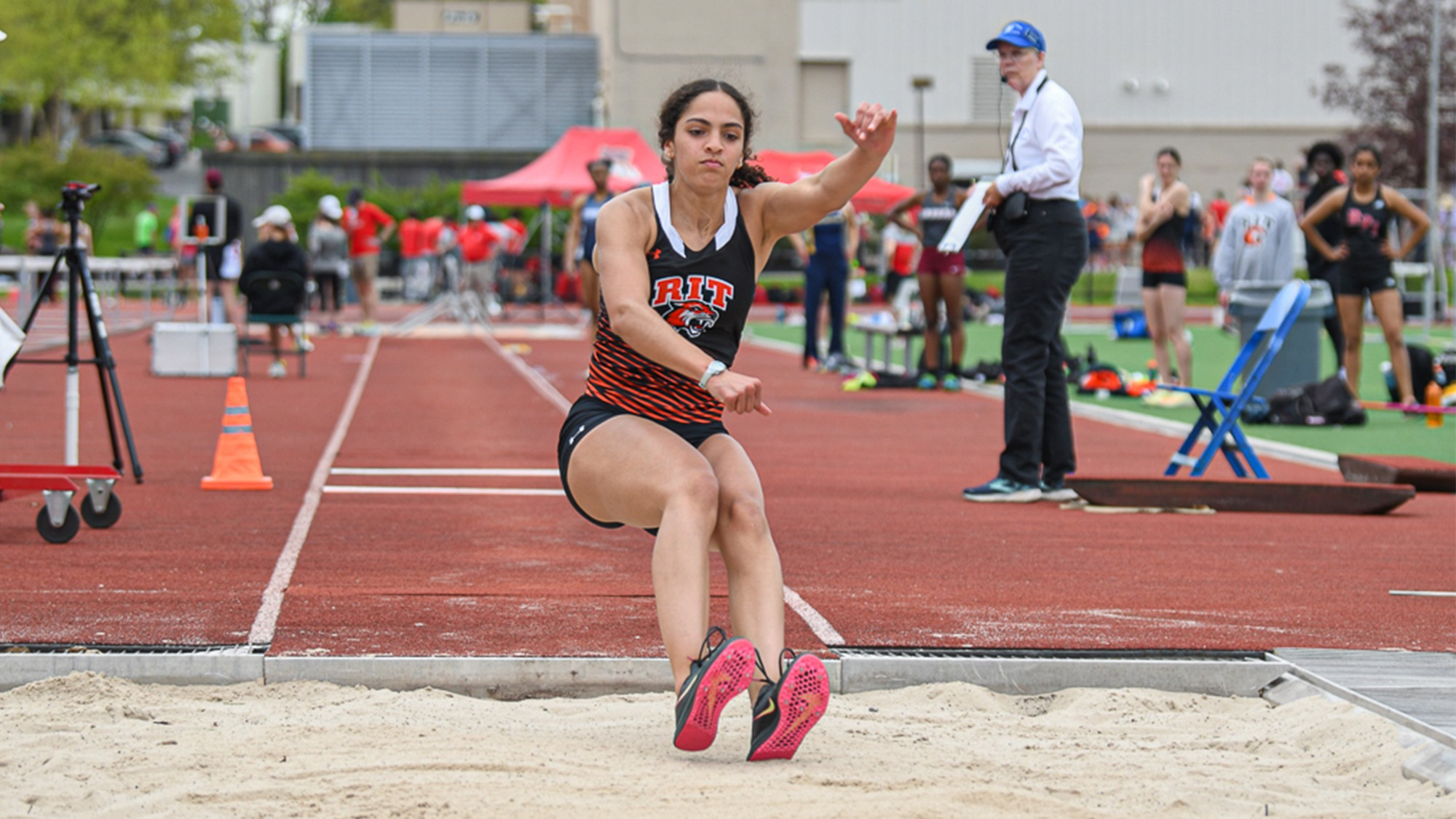 A women's track and field athlete lands in the sand pit after making an attempt in the long jump for Rochester Institute of Technology