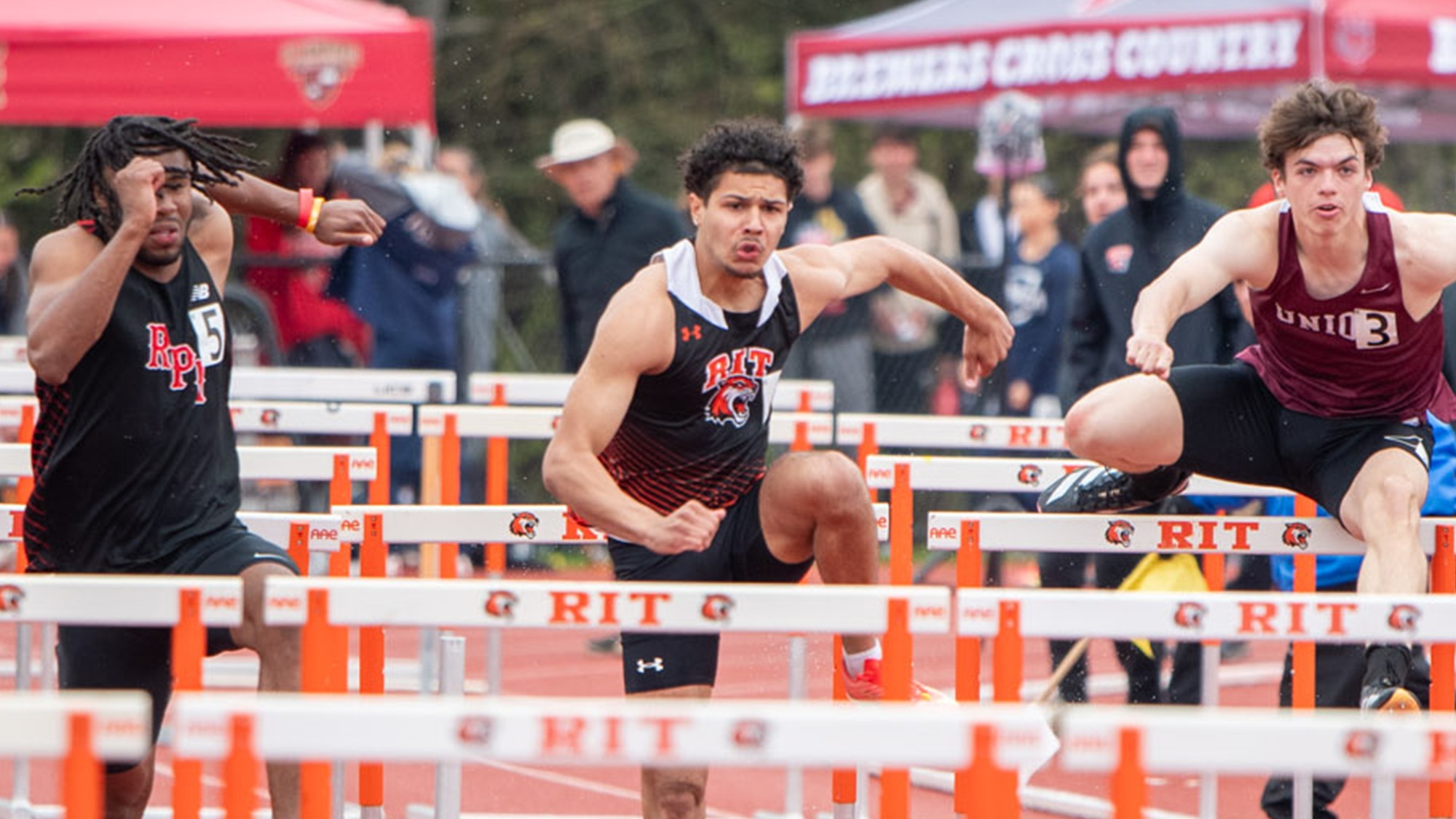 A men's hurdler competes in a race for the Rochester Institute of Technology men's track and field team