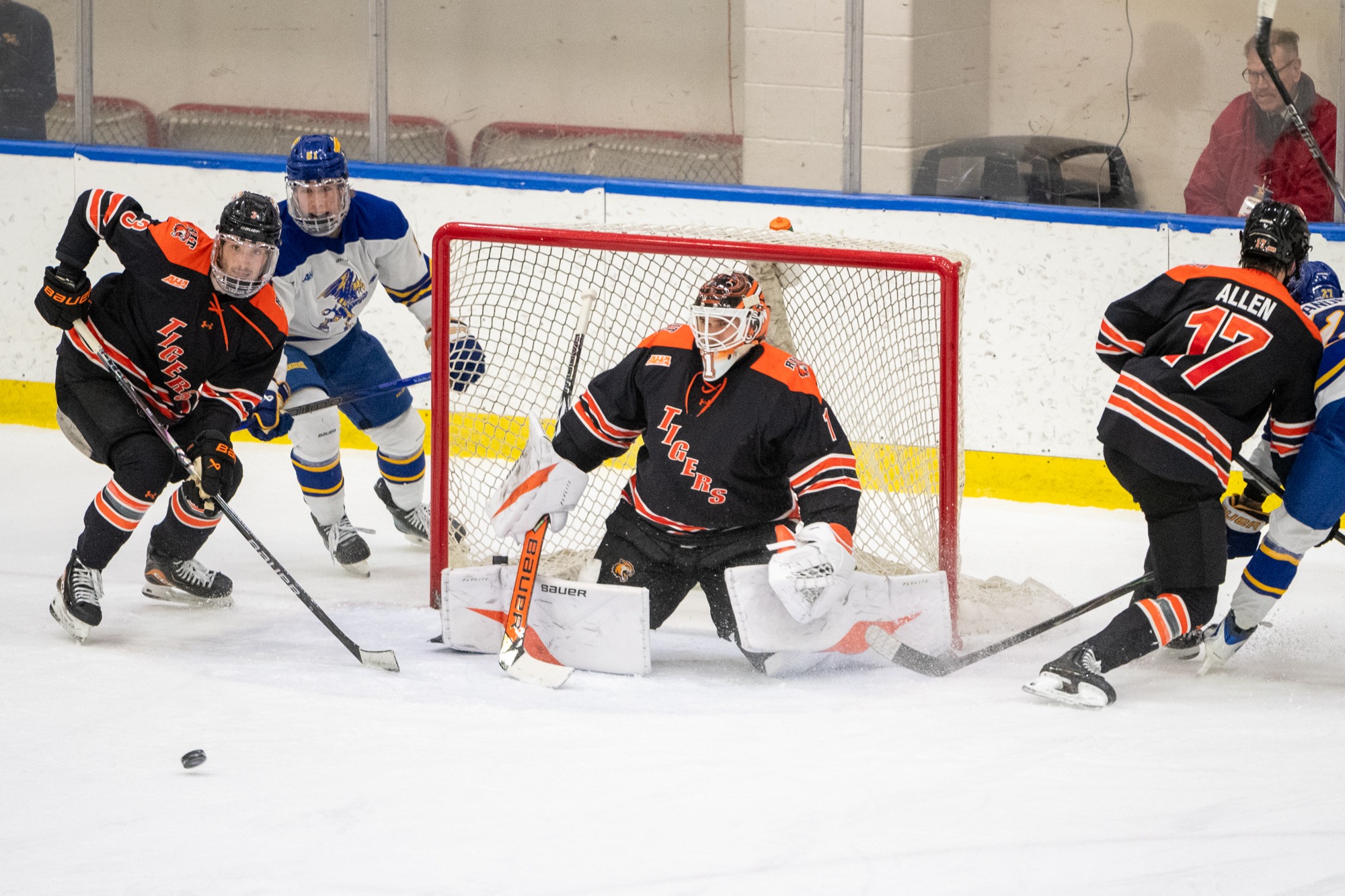 a goaltender getting ready to make a save in a crowd of players during a hockey game.