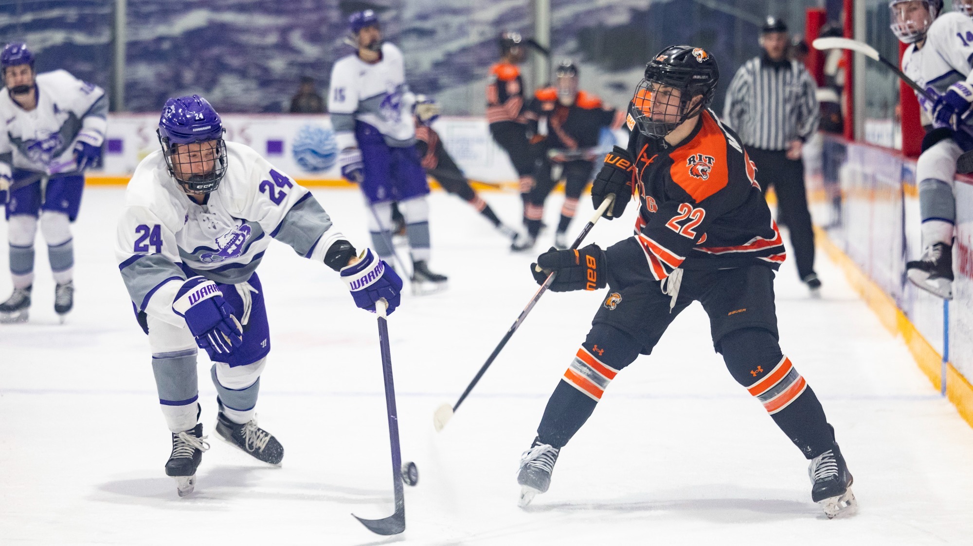 a men's hockey player passing a puck past a defender